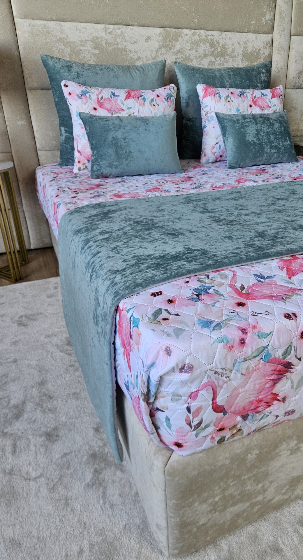 Cama com roupa de cama floral e almofadas em veludo azul esverdeado em quarto moderno