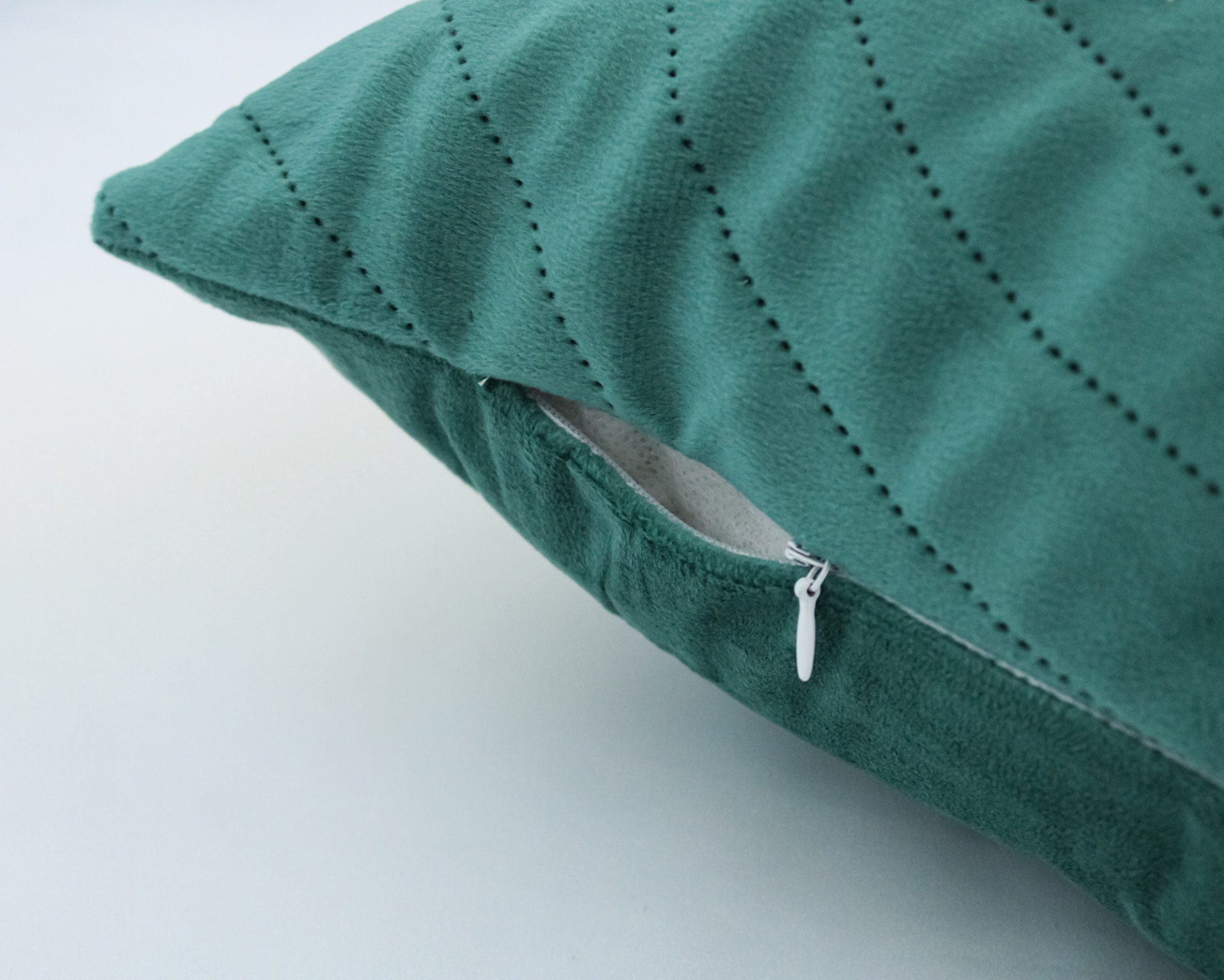 Almofada verde com linhas pontilhadas e fecho de correr