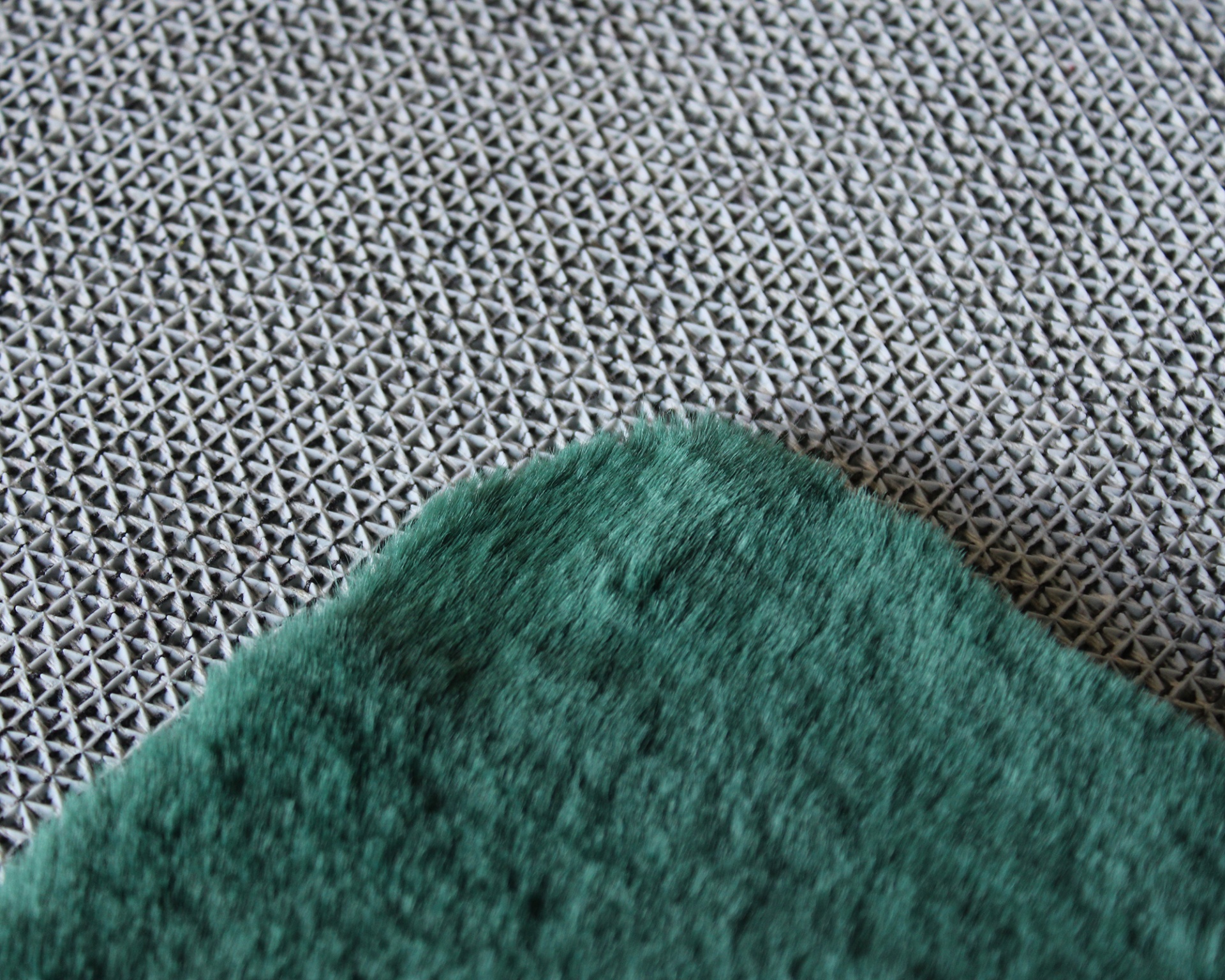 Detalhe de tecido verde felpudo sobre superfície com padrão geométrico preto e branco