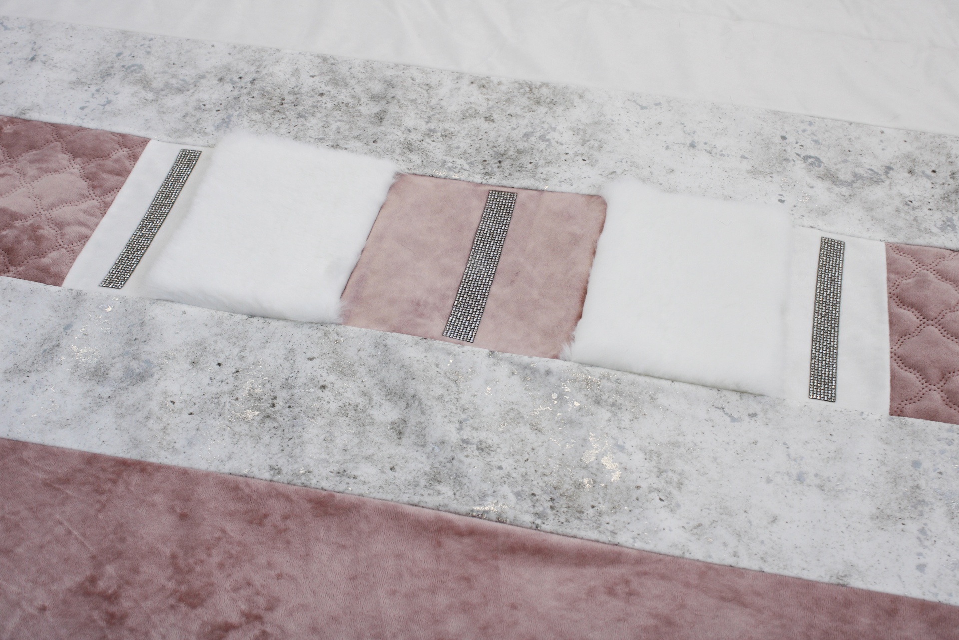 Colcha com padrões em rosa, branco e cinza, texturas macias e detalhes em trapunto