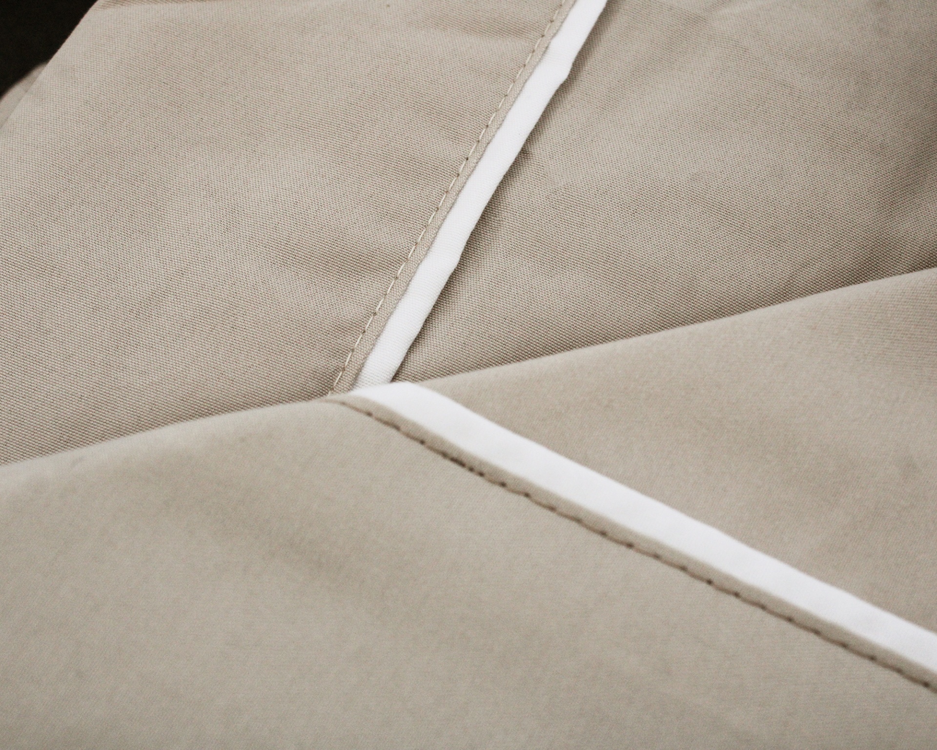 Detalhe de tecido bege com costura e faixa branca