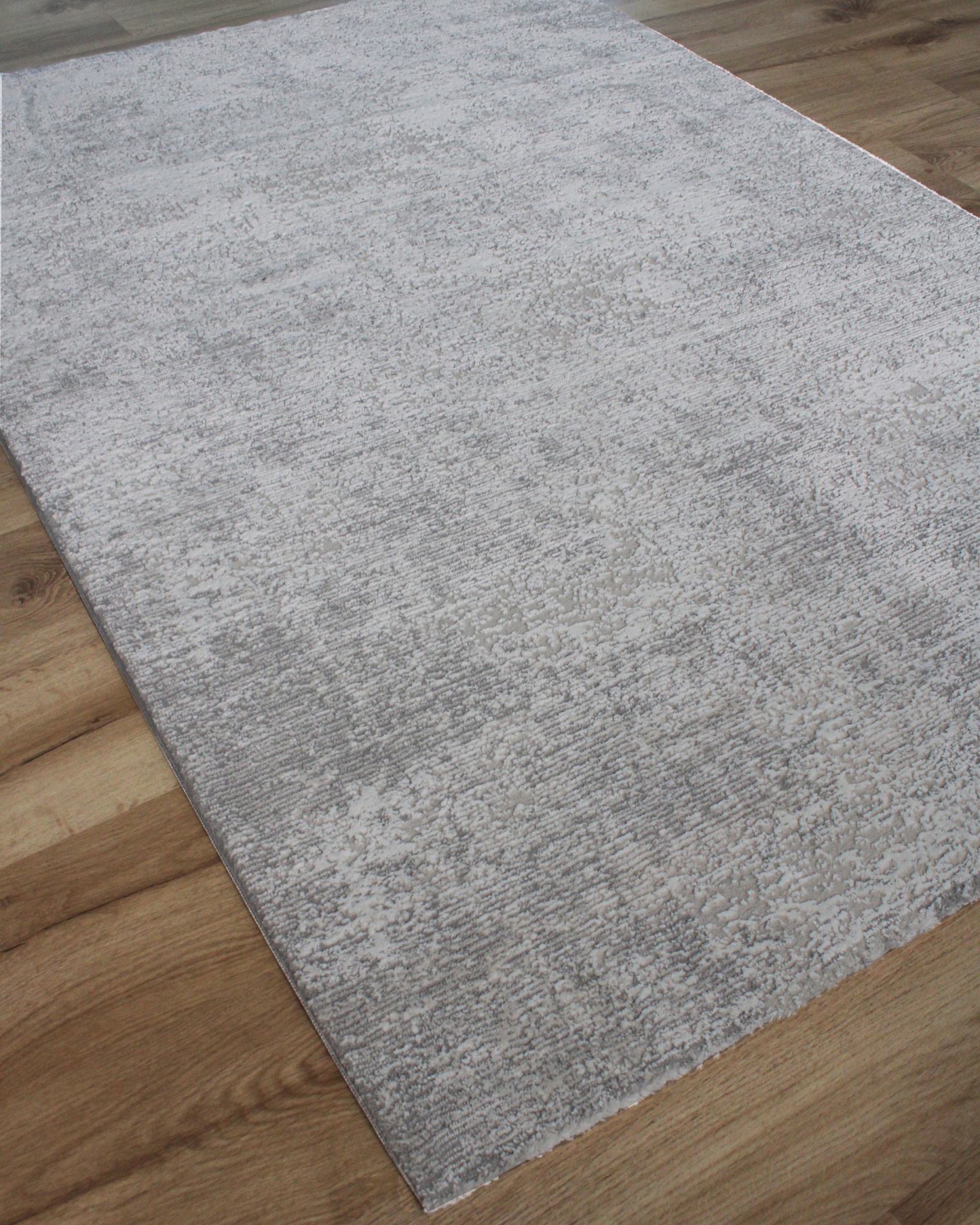 Tapete cinzento claro com padrão texturizado num chão de madeira clara