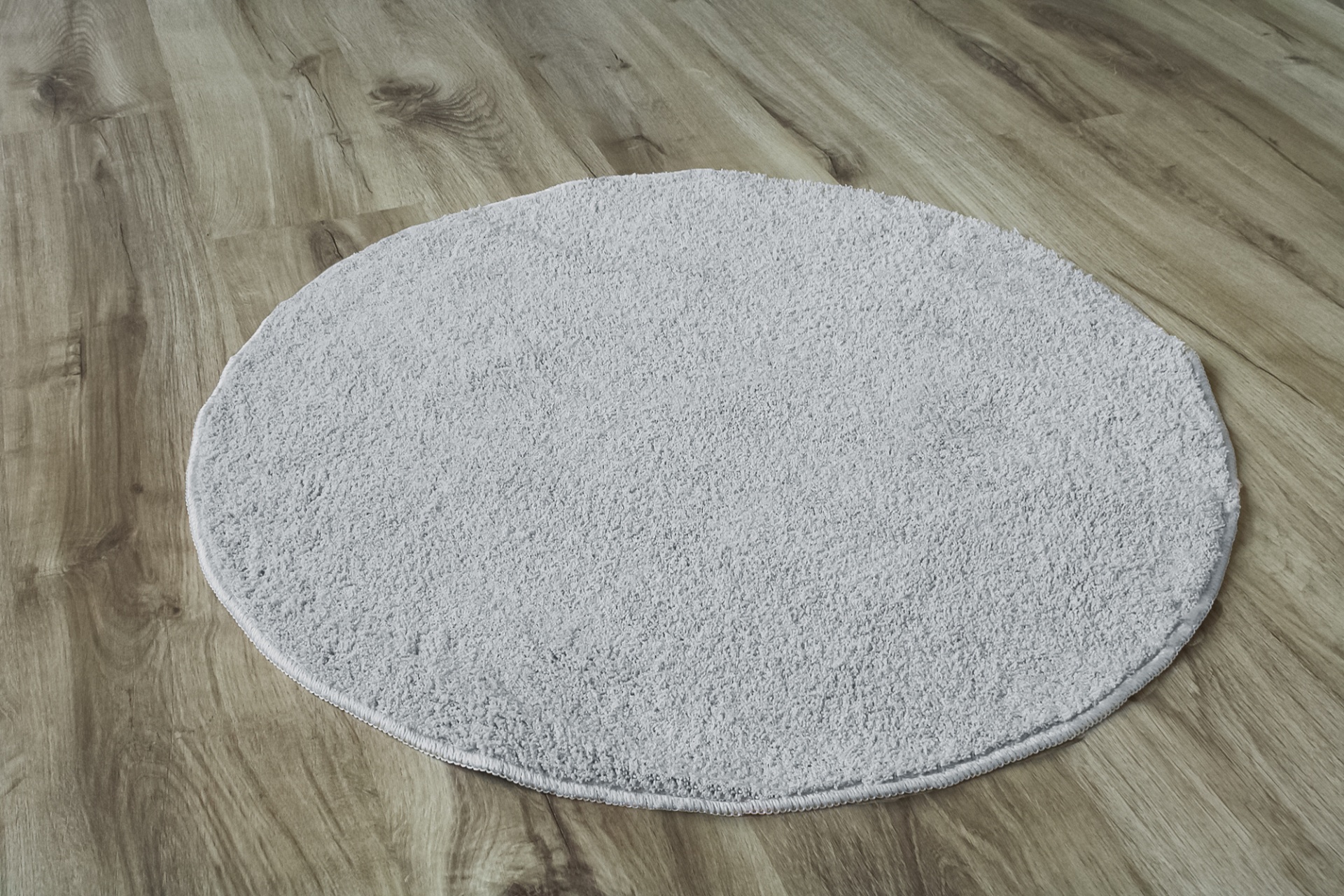 Tapete redondo cinza claro sobre chão de madeira clara