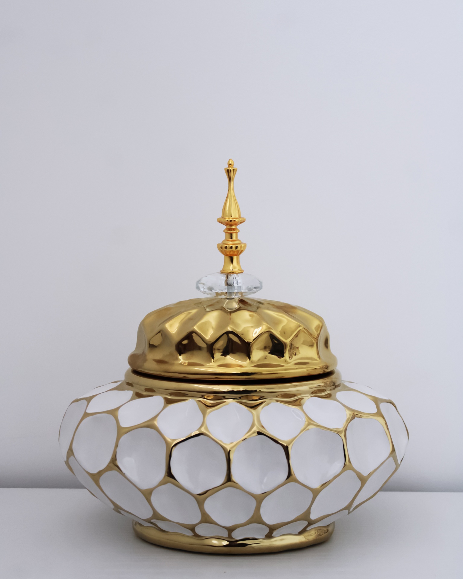 Recipiente decorativo com tampa dourada e corpo branco com padrão dourado