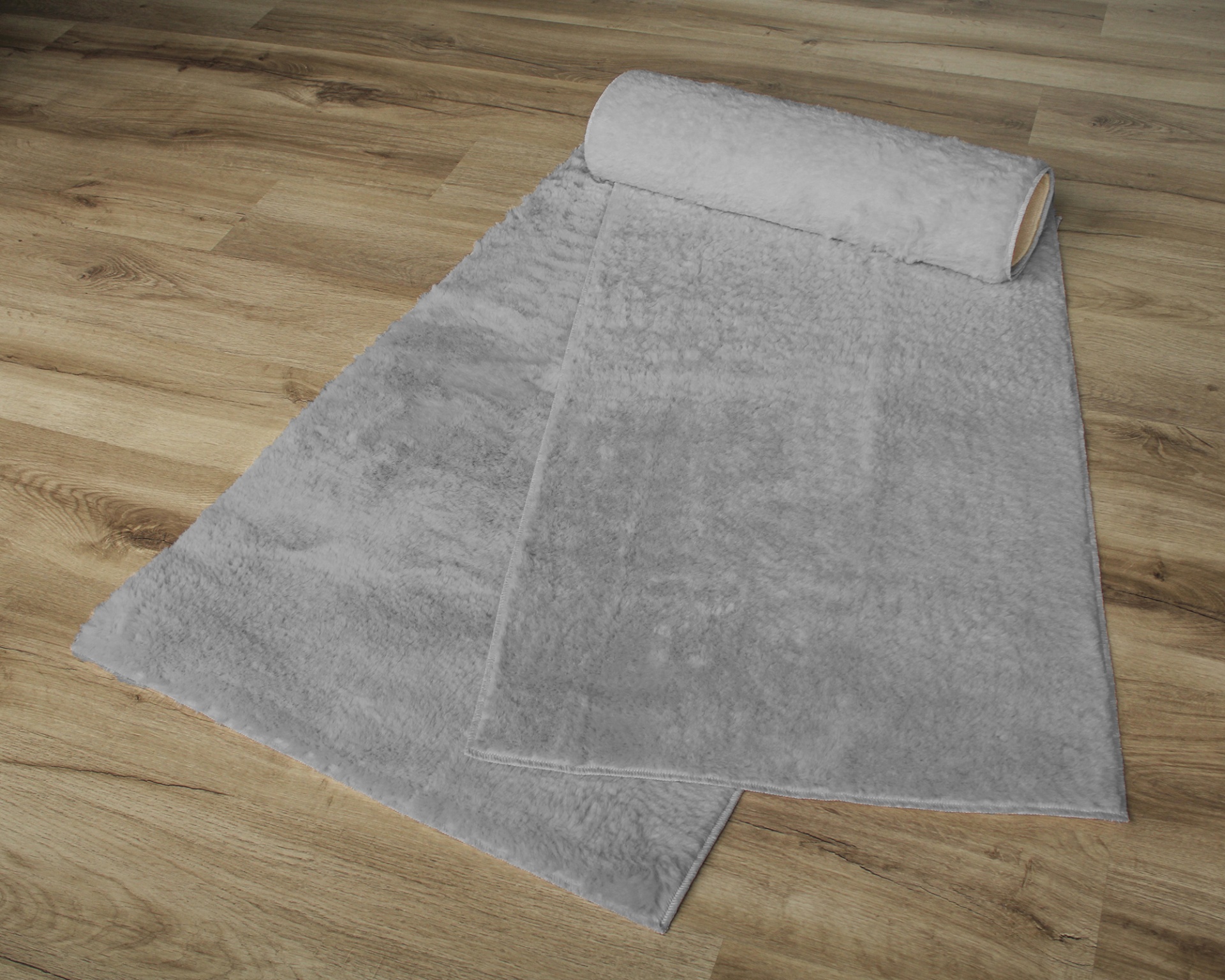 Tapete cinza claro com textura macia desenrolado no chão de madeira