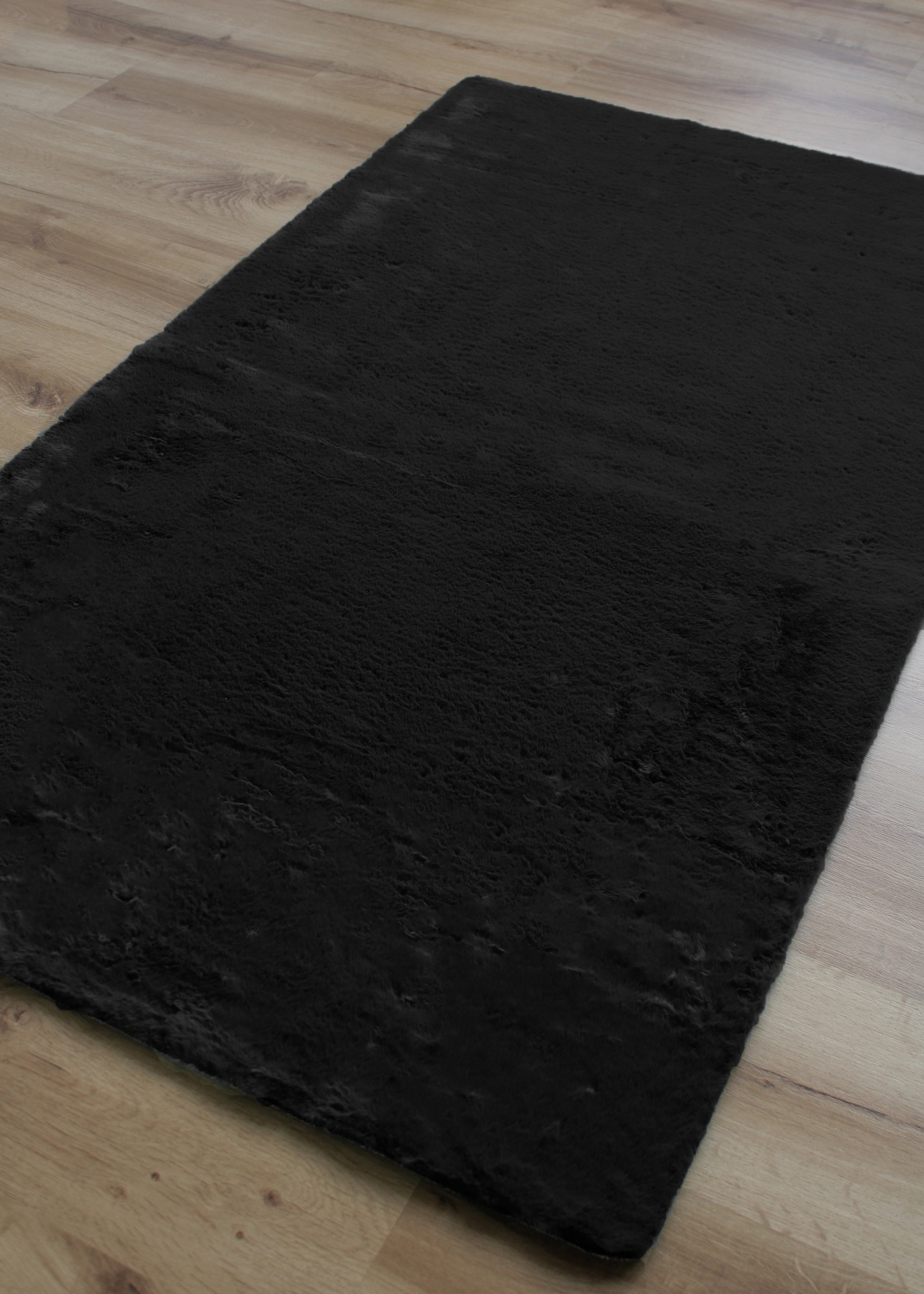 Tapete preto felpudo sobre chão de madeira clara