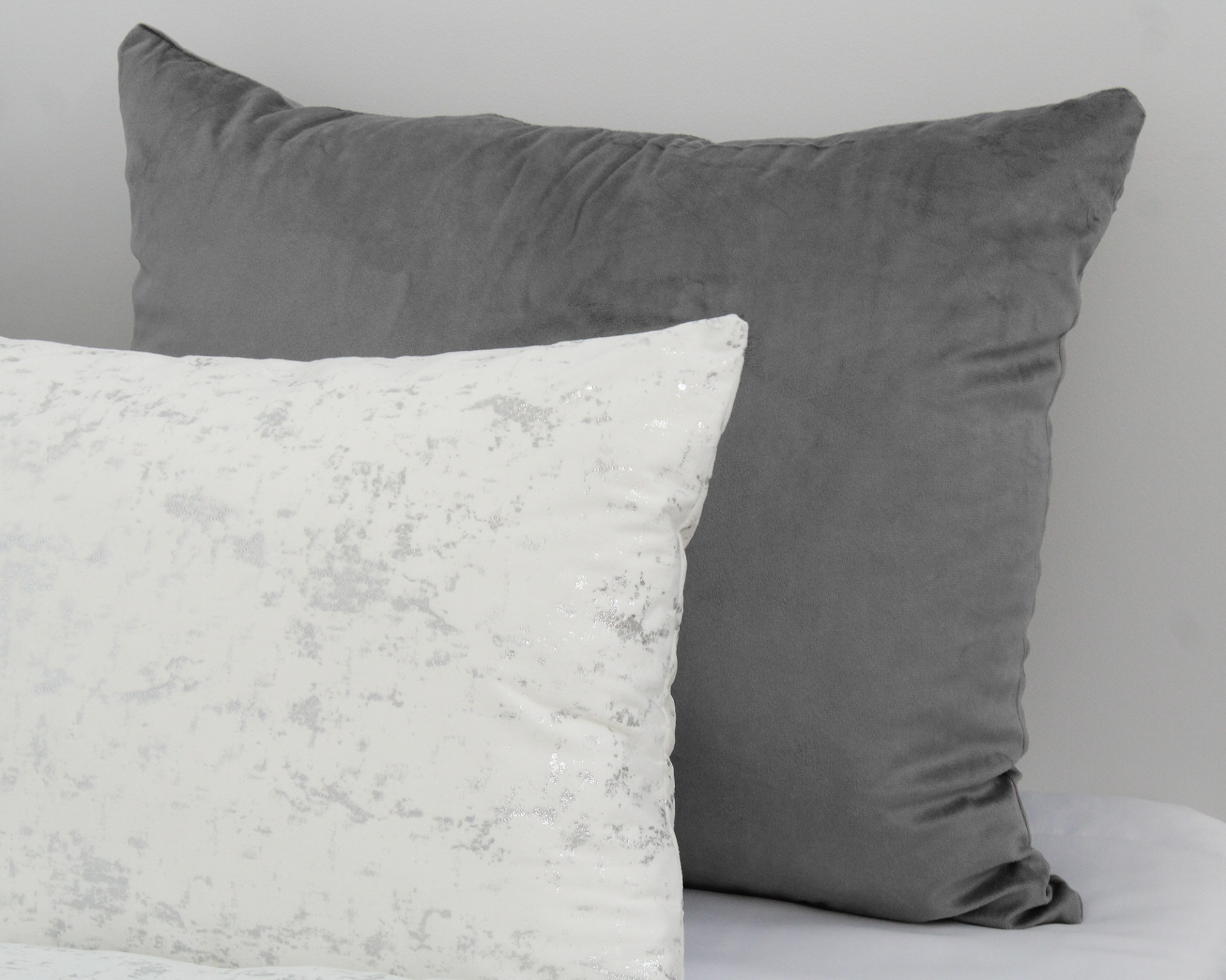 Duas almofadas, uma cinza e outra branca com padrão prateado
