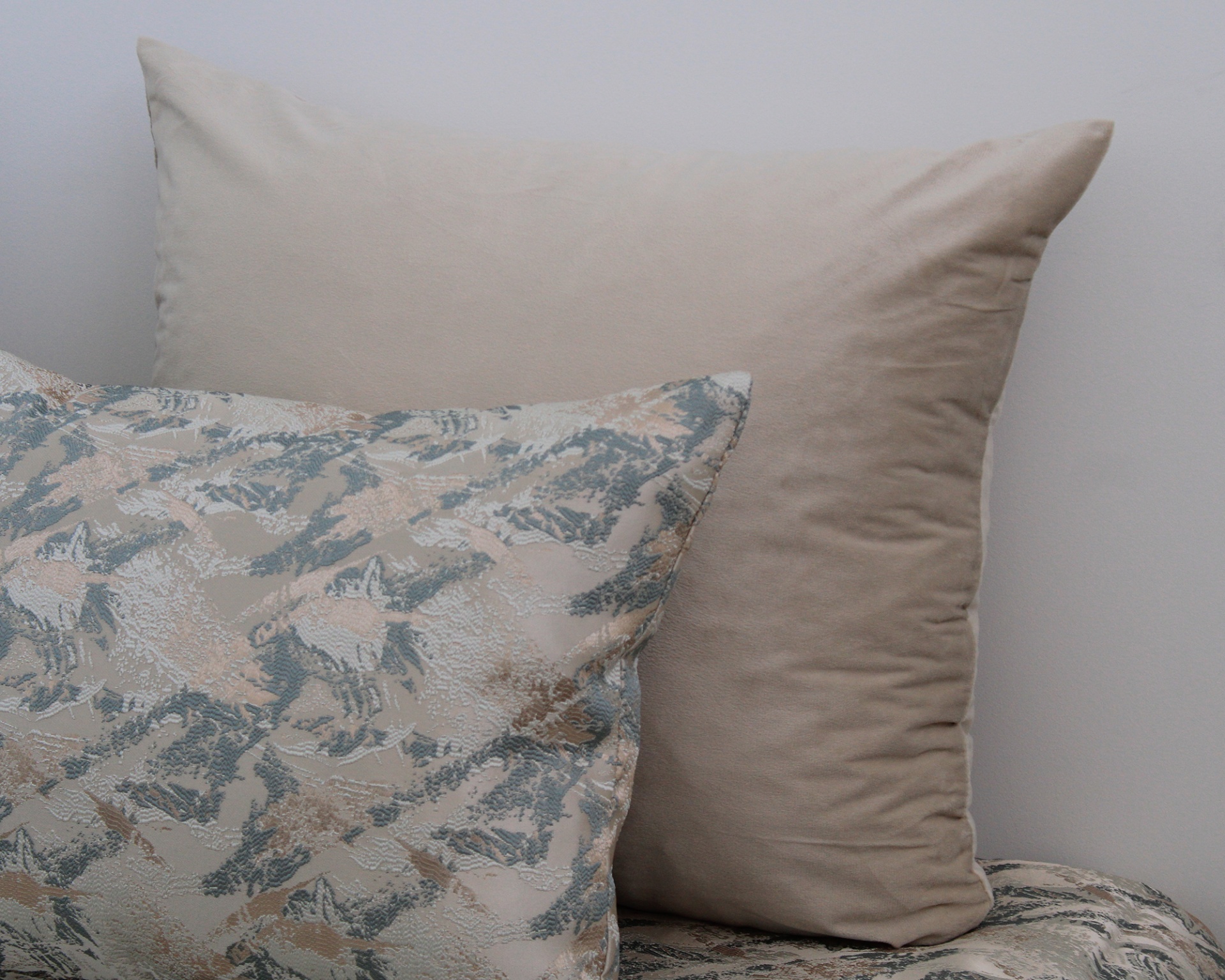 Almofadas bege lisas e com padrão abstrato cinza, bege e azul