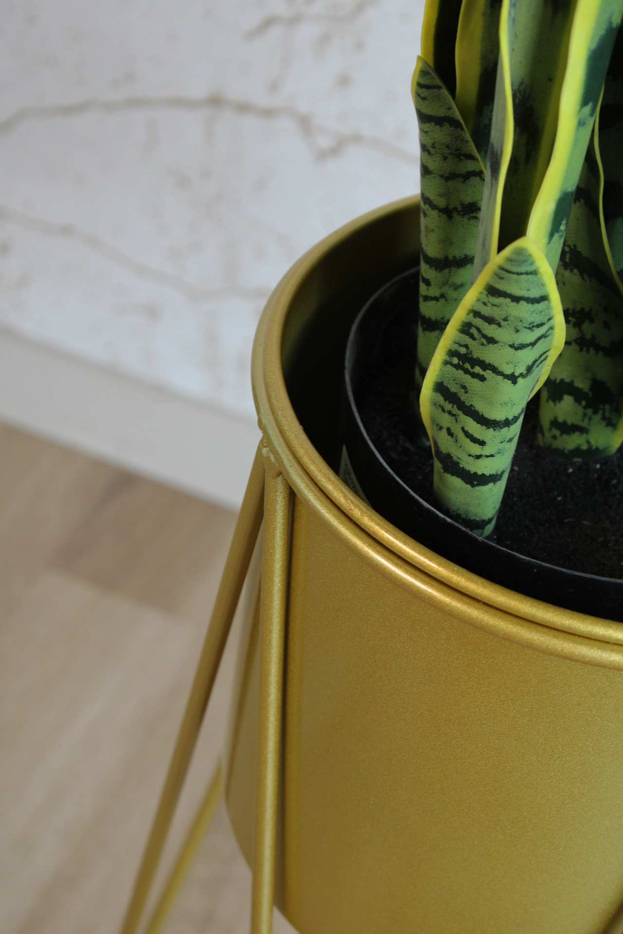 Vaso dourado com planta artificial verde e amarela em suporte metálico