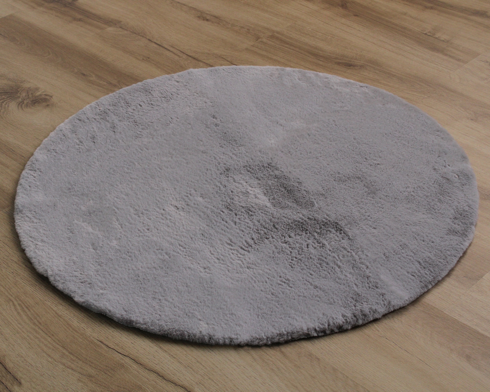 Tapete redondo cinza claro felpudo sobre chão de madeira clara