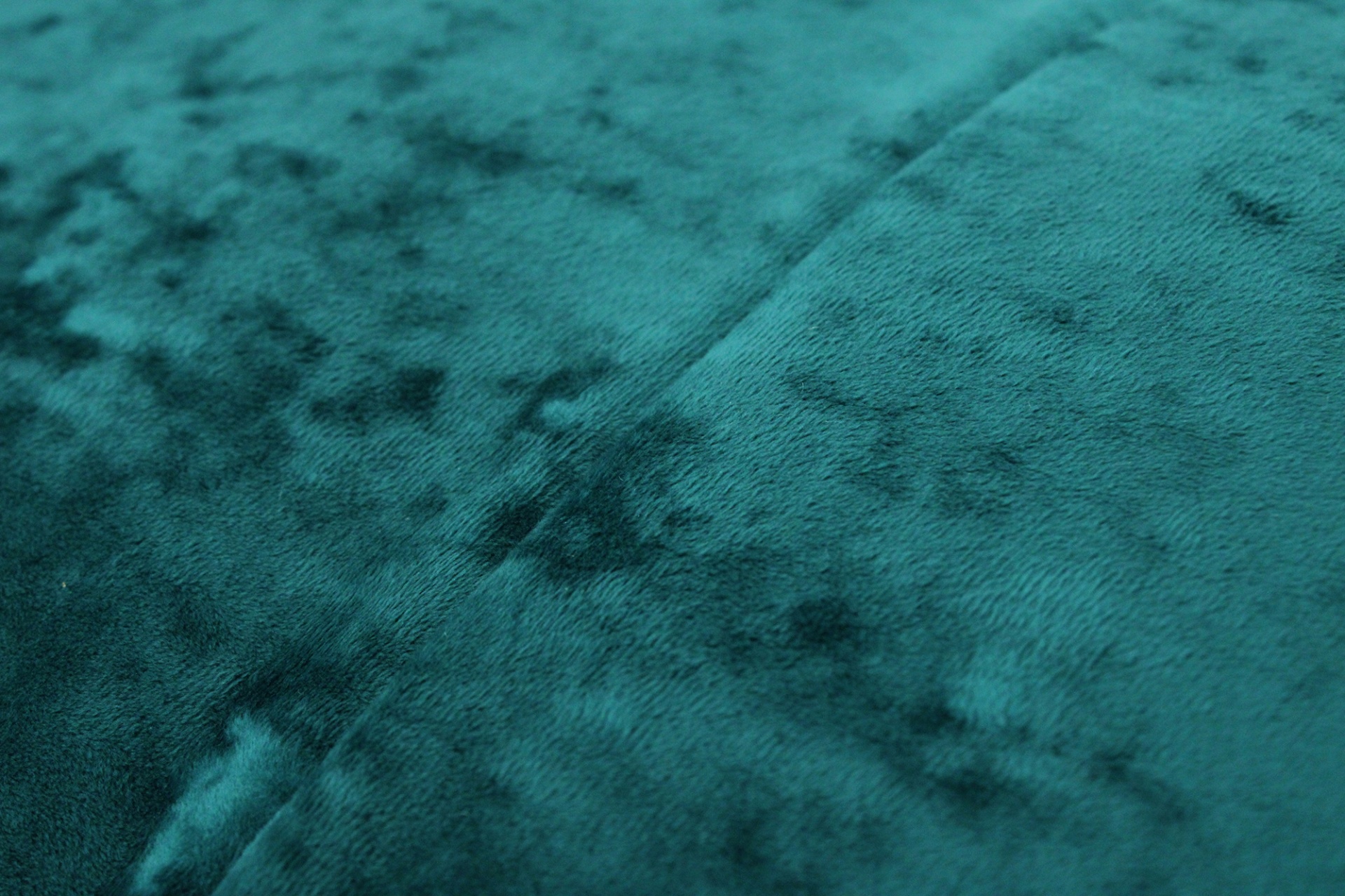 Tecido azul-esverdeado de veludo com textura macia e costura no centro