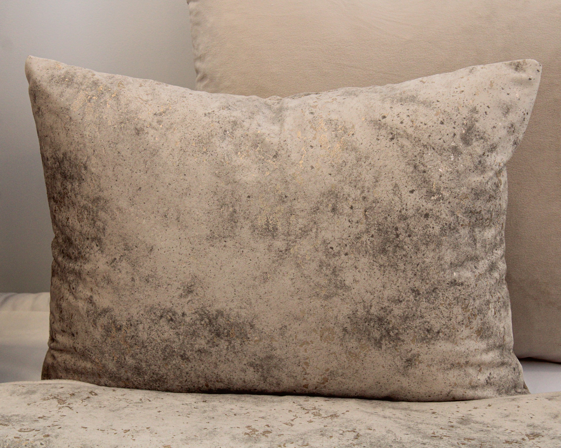 Três almofadas em tecido bege com padrão marmorizado e textura aveludada
