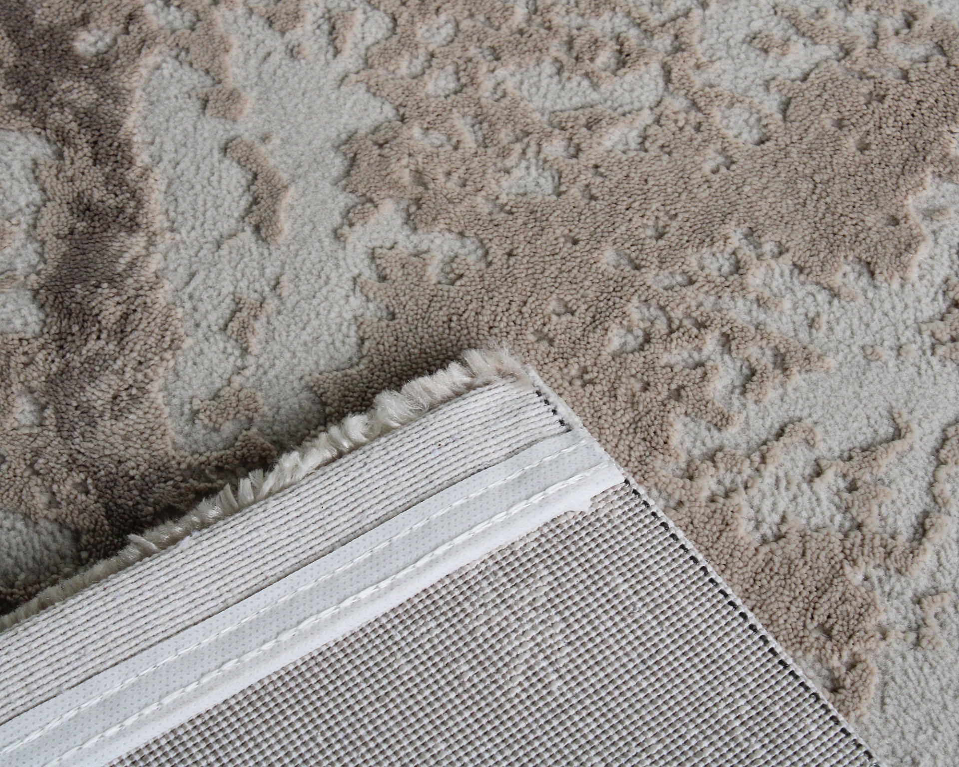 Tapete bege e cinza claro com textura felpuda e parte inferior branca com franjas