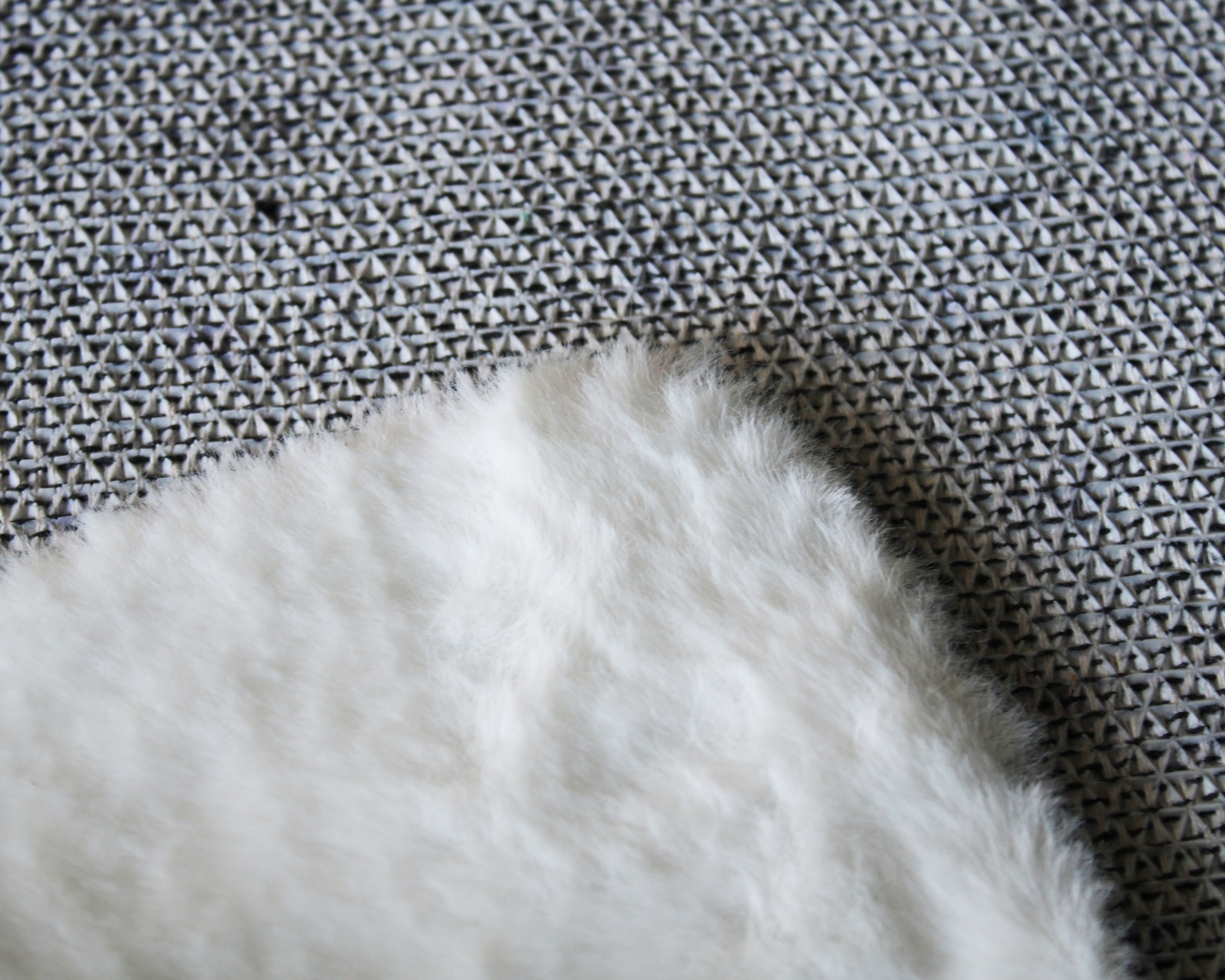 Cobertor branco felpudo sobre superfície com padrão geométrico preto e branco