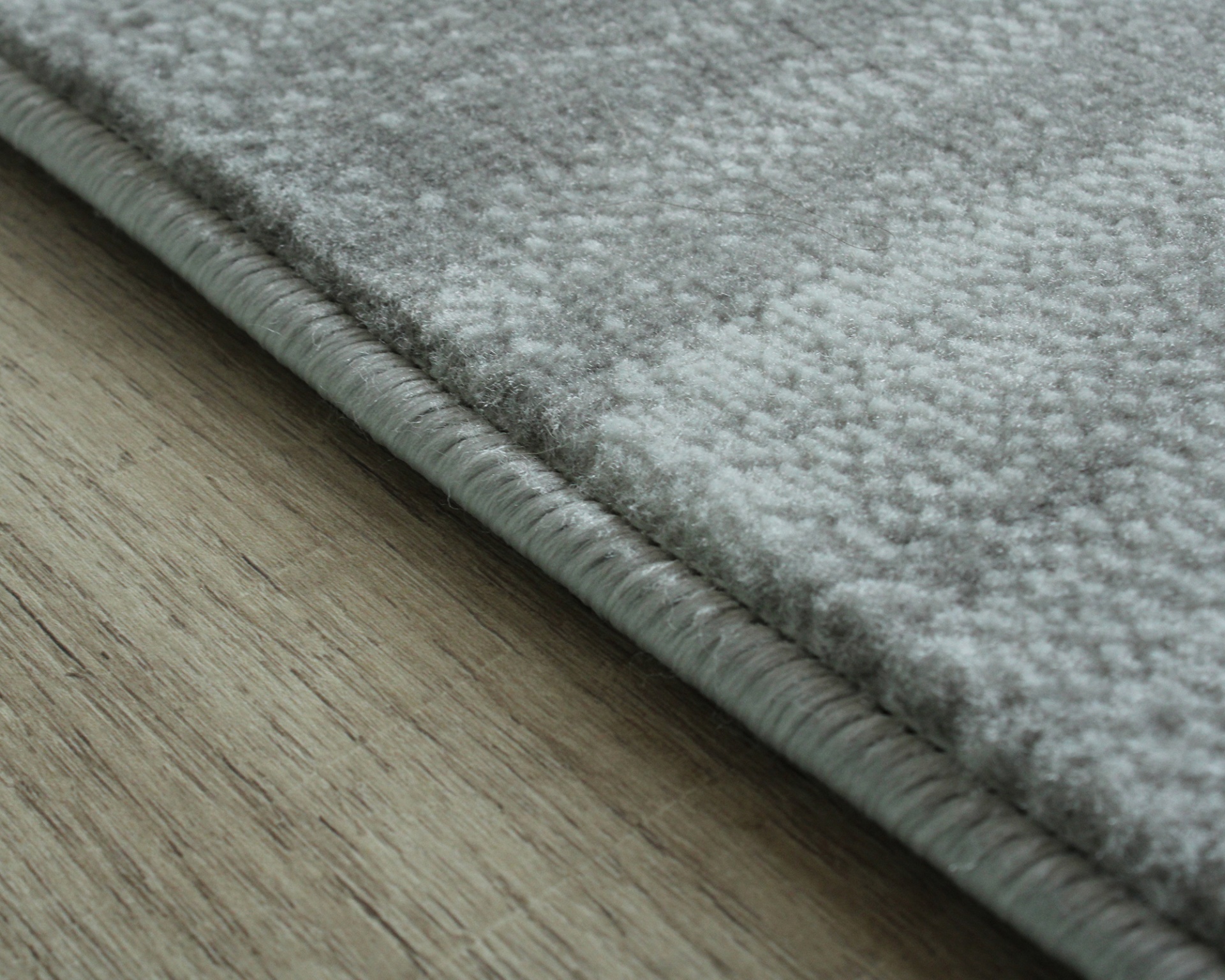 Tapete cinzento claro com textura macia sobre chão de madeira