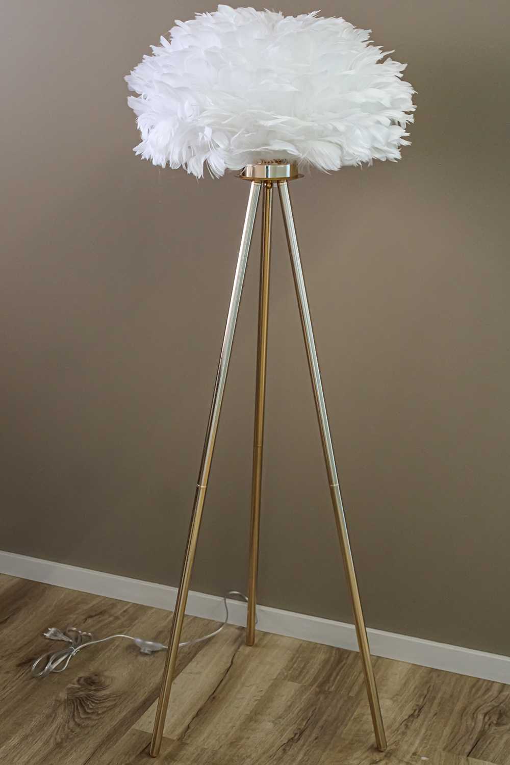 Lâmpada de pé com abajur de penas brancas e base metálica dourada tripé