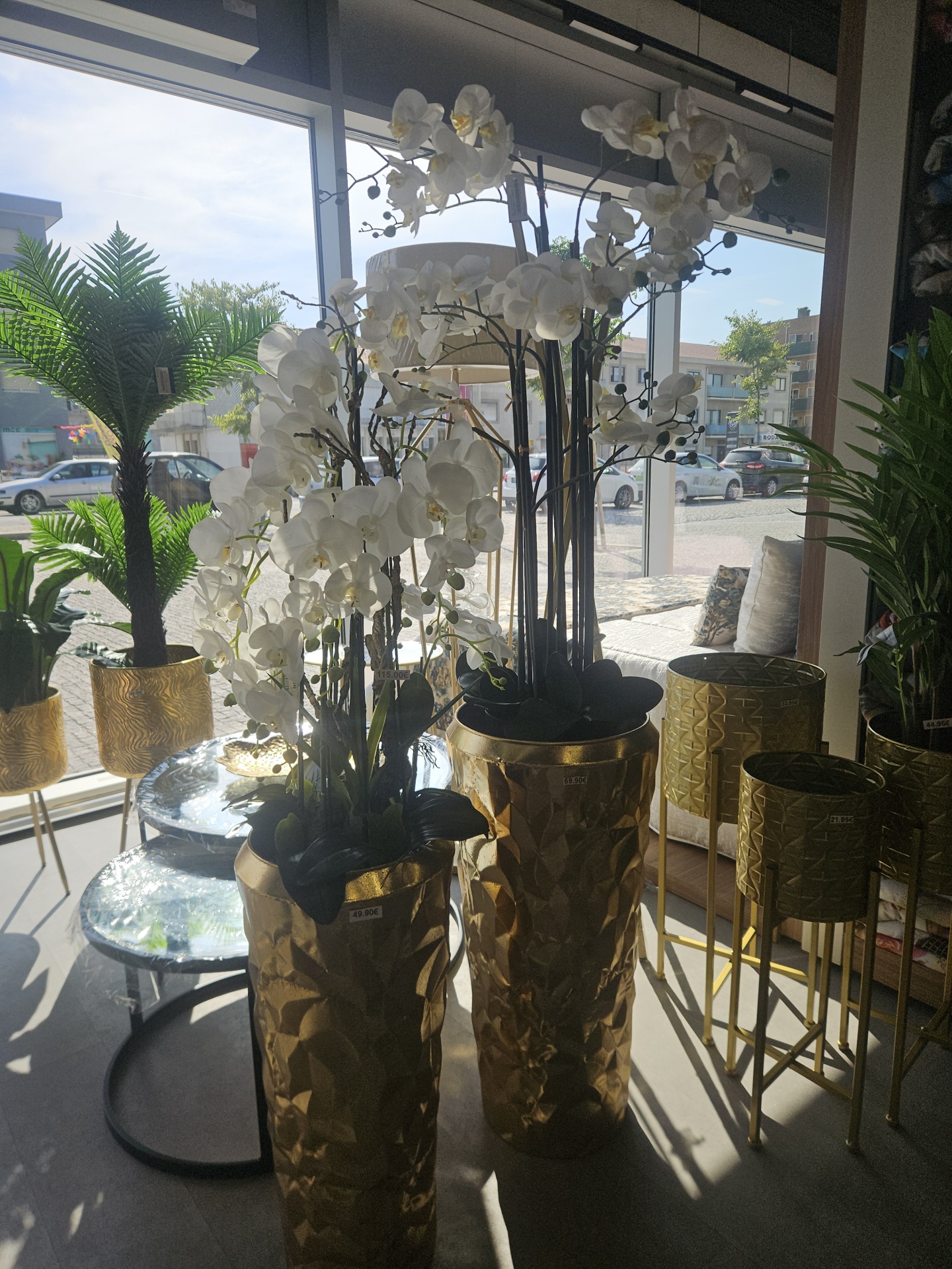 Orquídeas brancas artificiais em vasos dourados numa loja
