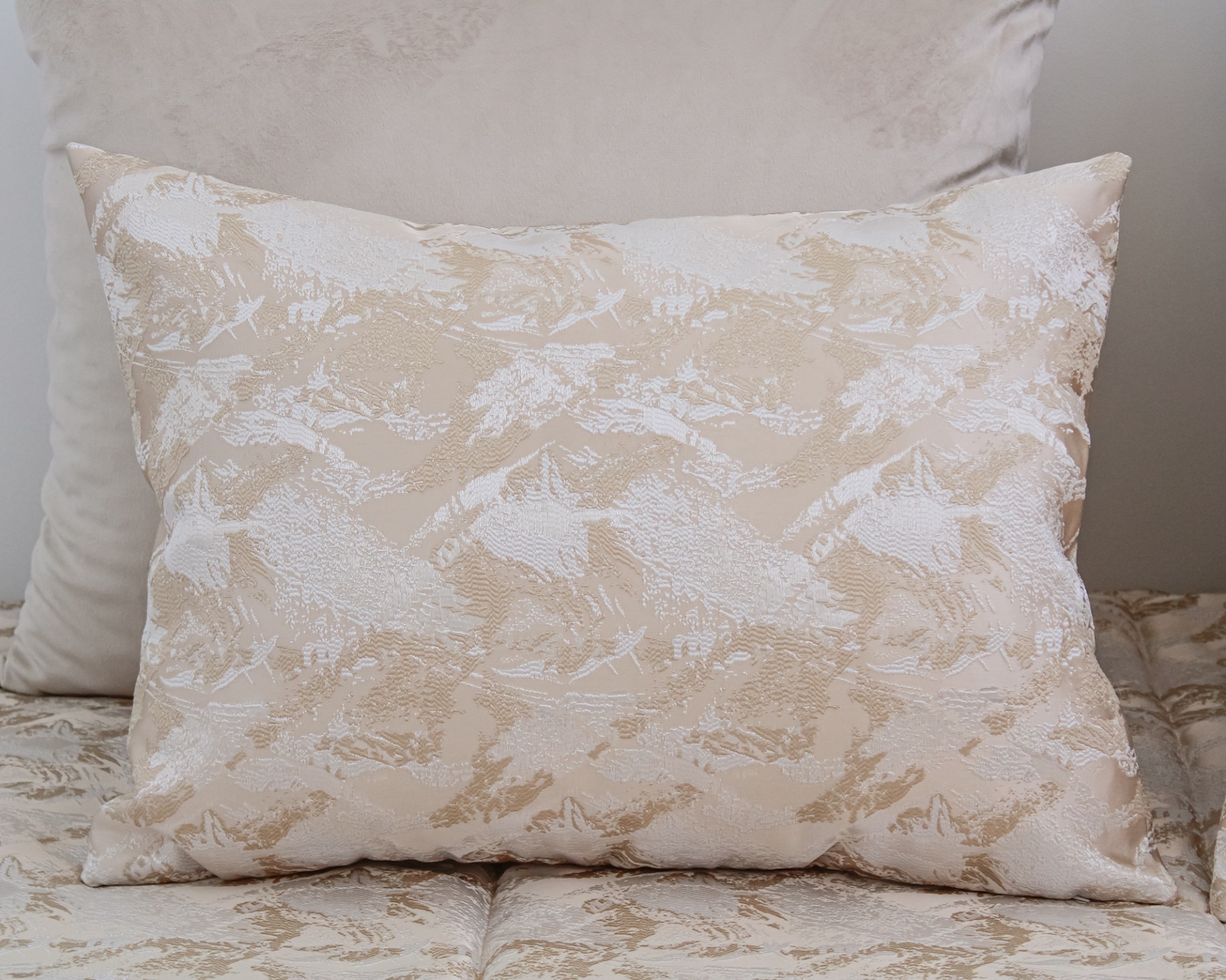 Almofada retangular bege e branca com textura jacquard