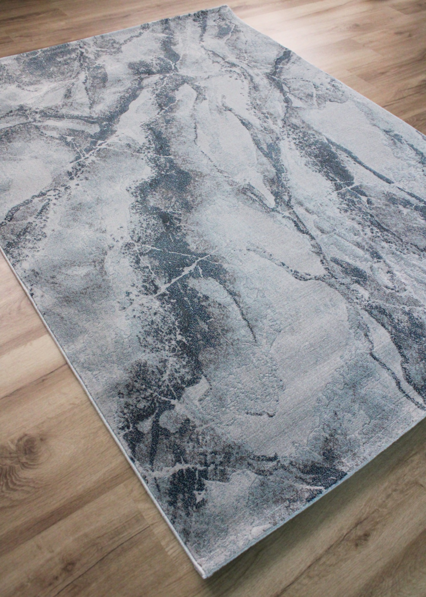 Tapete cinza e azul com padrão abstrato sobre chão de madeira clara