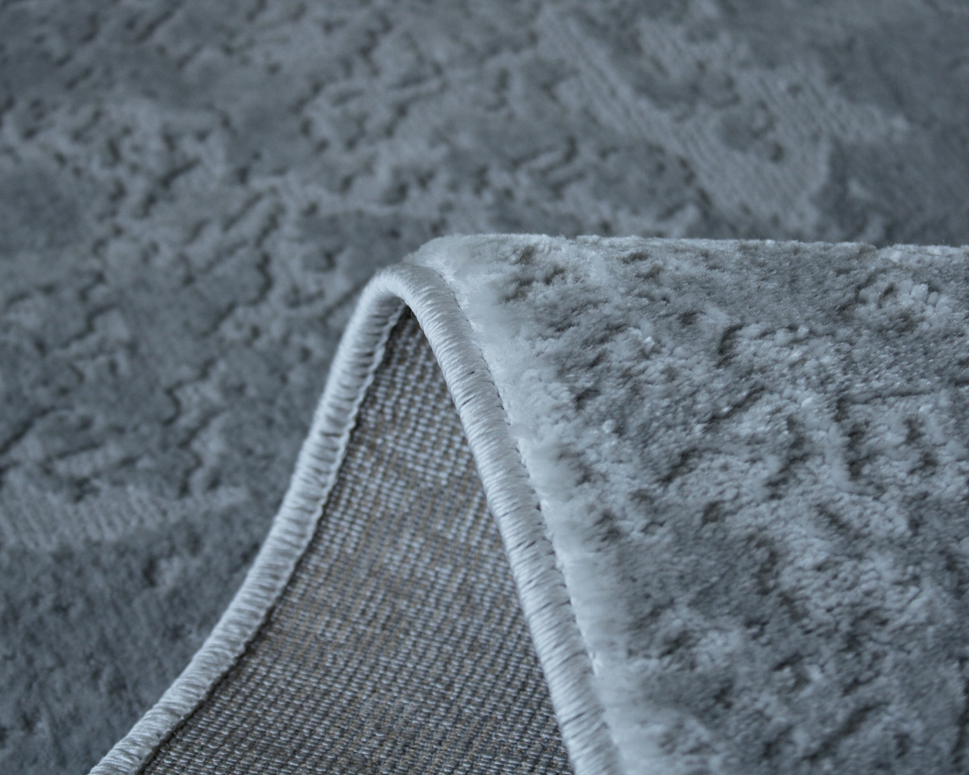 Tapete cinzento com padrão texturizado e costura branca dobrado