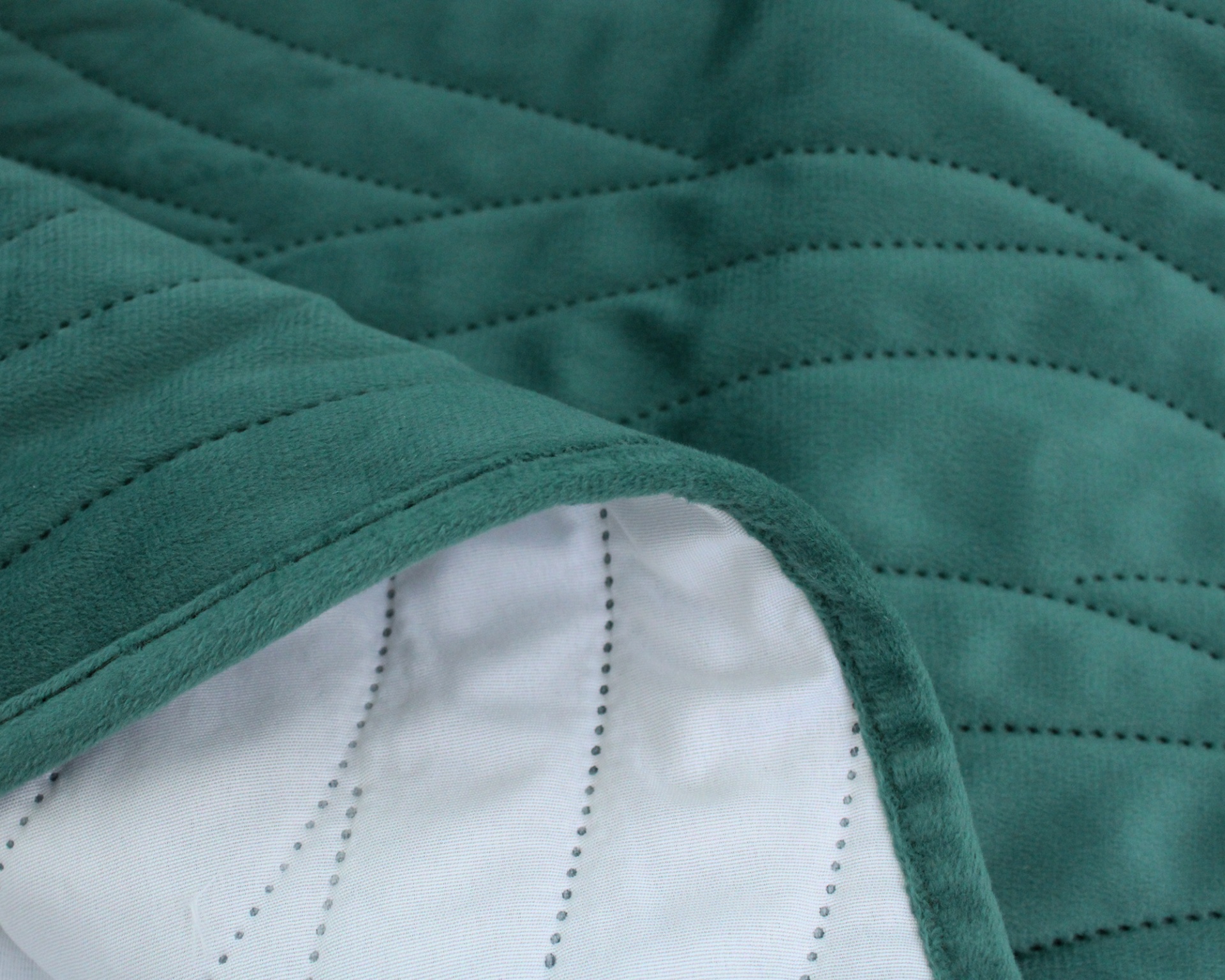 Colcha acolchoada verde com interior branco visível