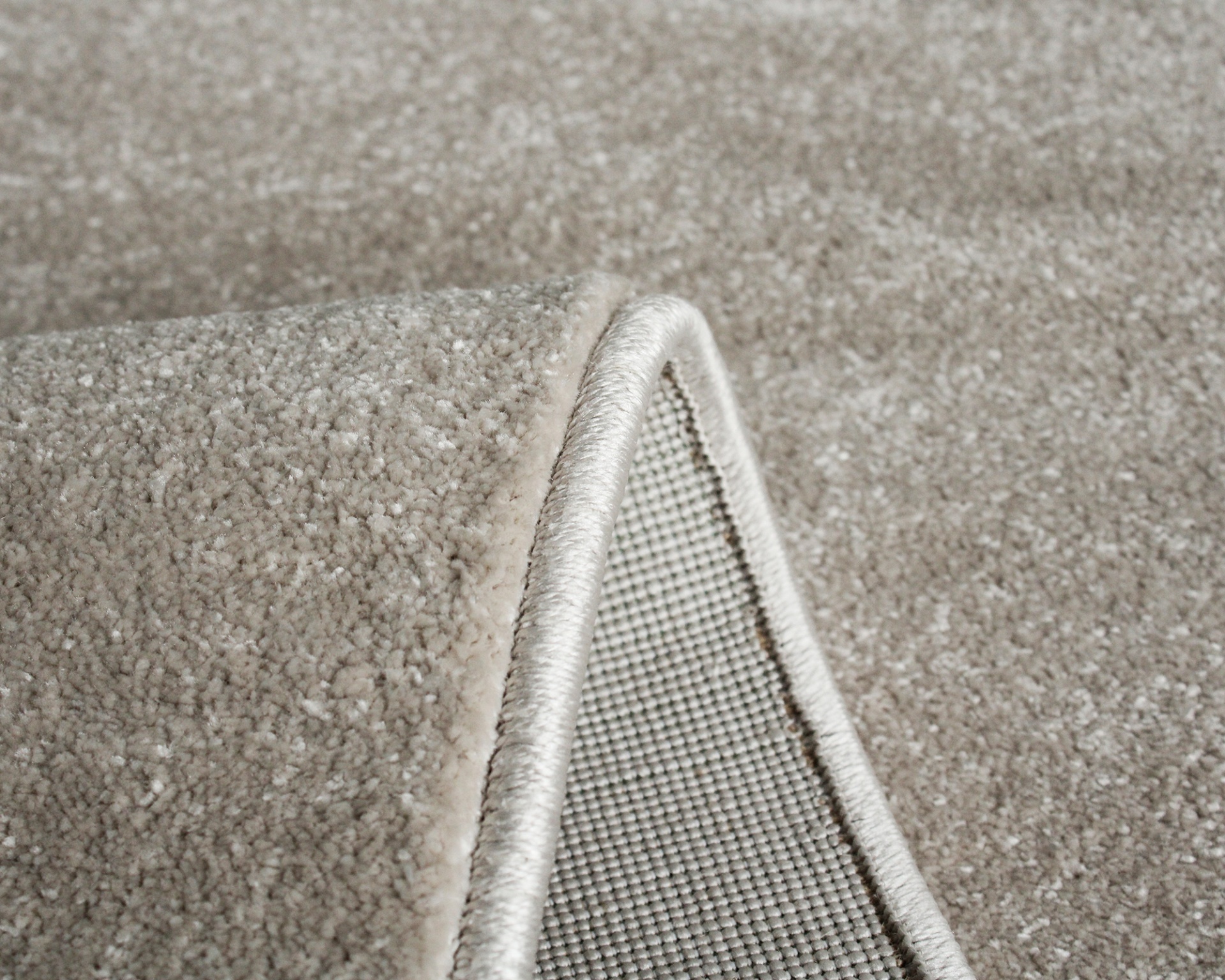 Close-up de tapete de carpete bege claro com bordas rematadas e parte inferior antiderrapante
