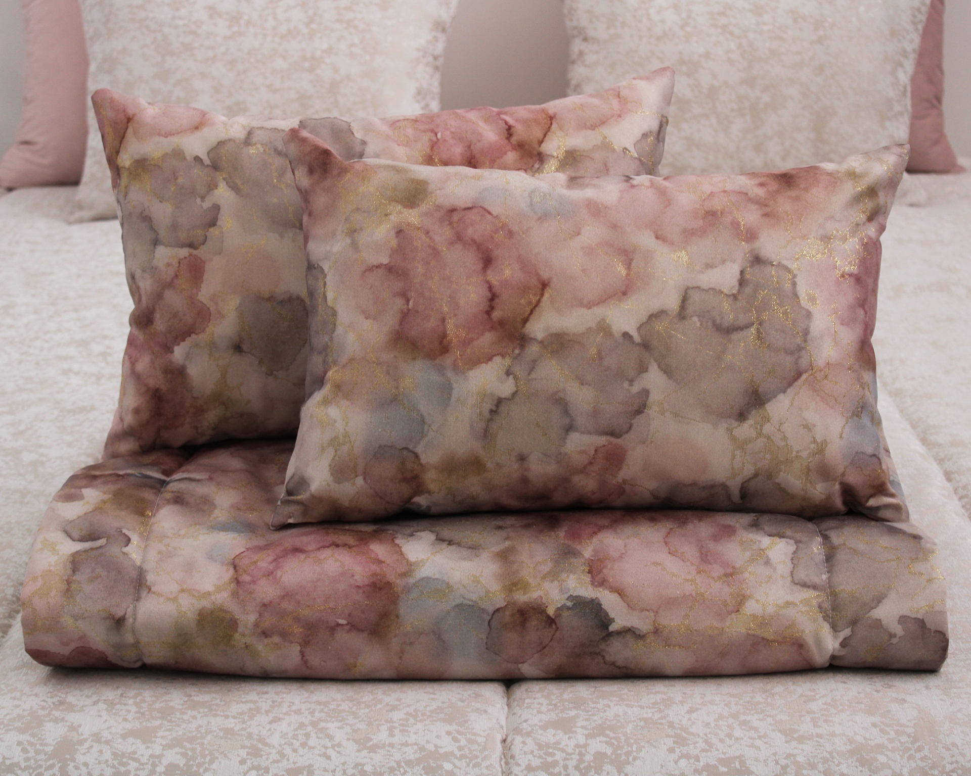 Conjunto de cama com padrão abstrato em tons rosa, cinza, azul e dourado