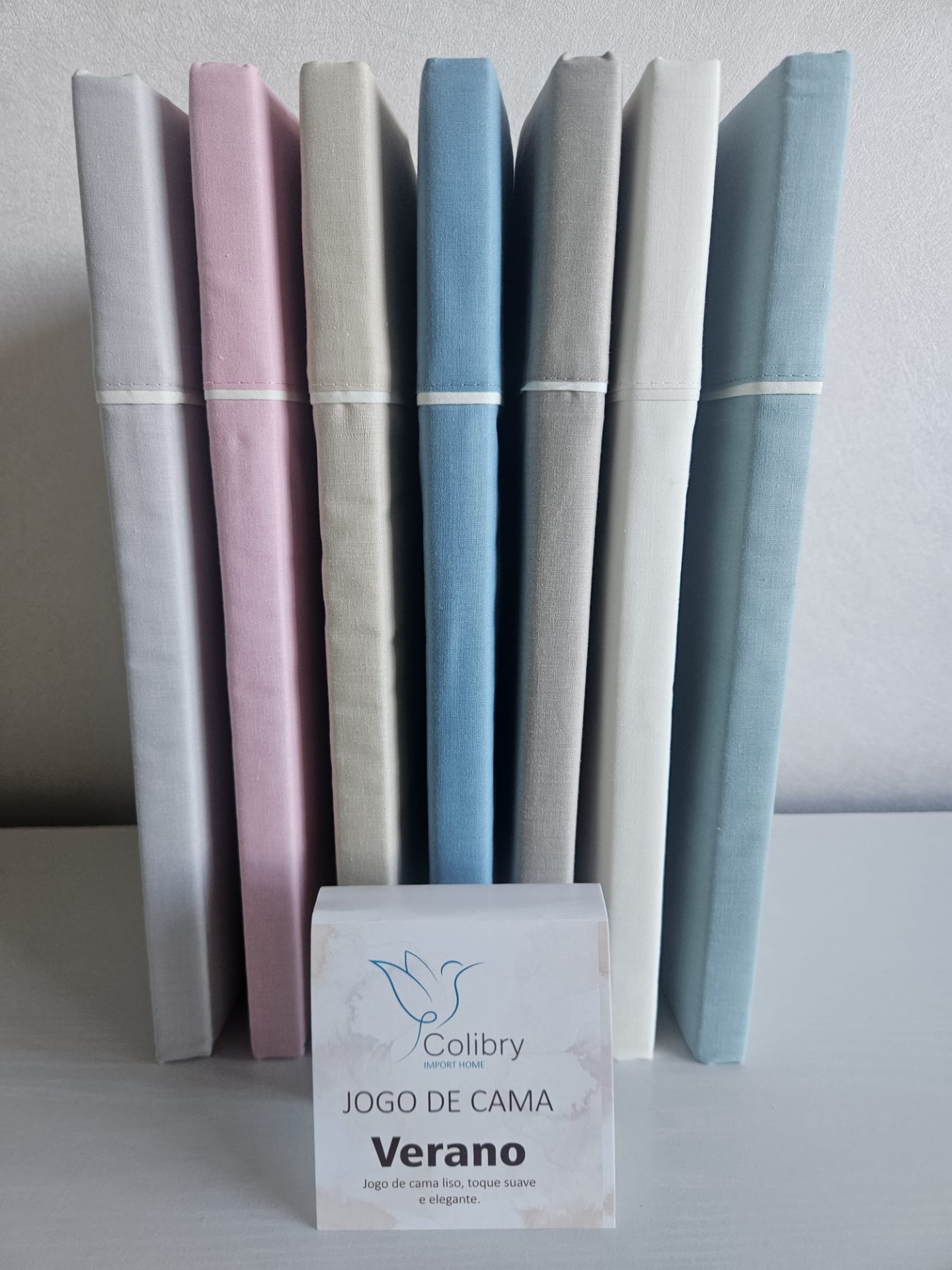 Pacotes de jogo de cama em várias cores pastel com etiqueta de marca e descrição na frente