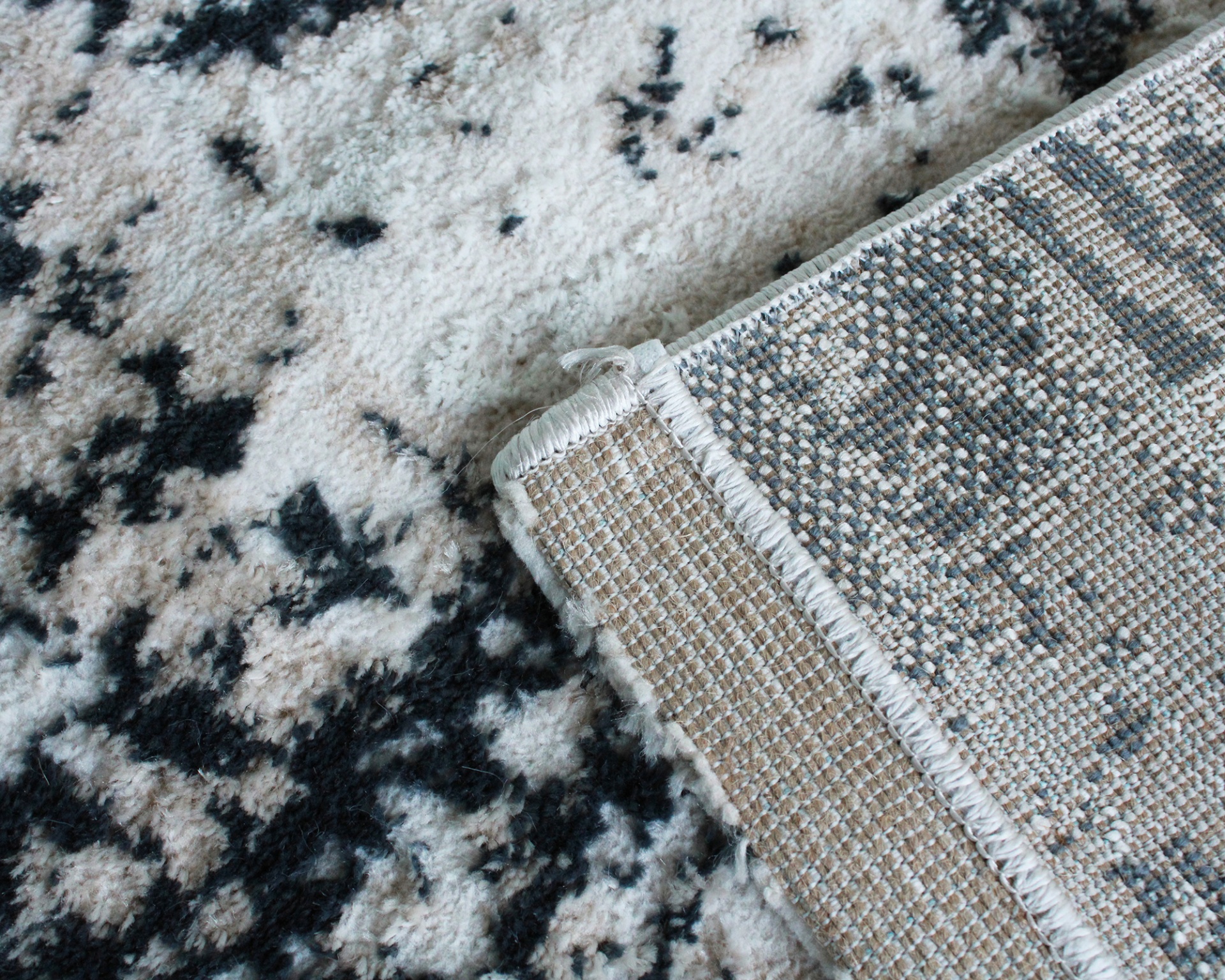 Tapete com padrão abstrato em tons claros e escuros com ponta dobrada