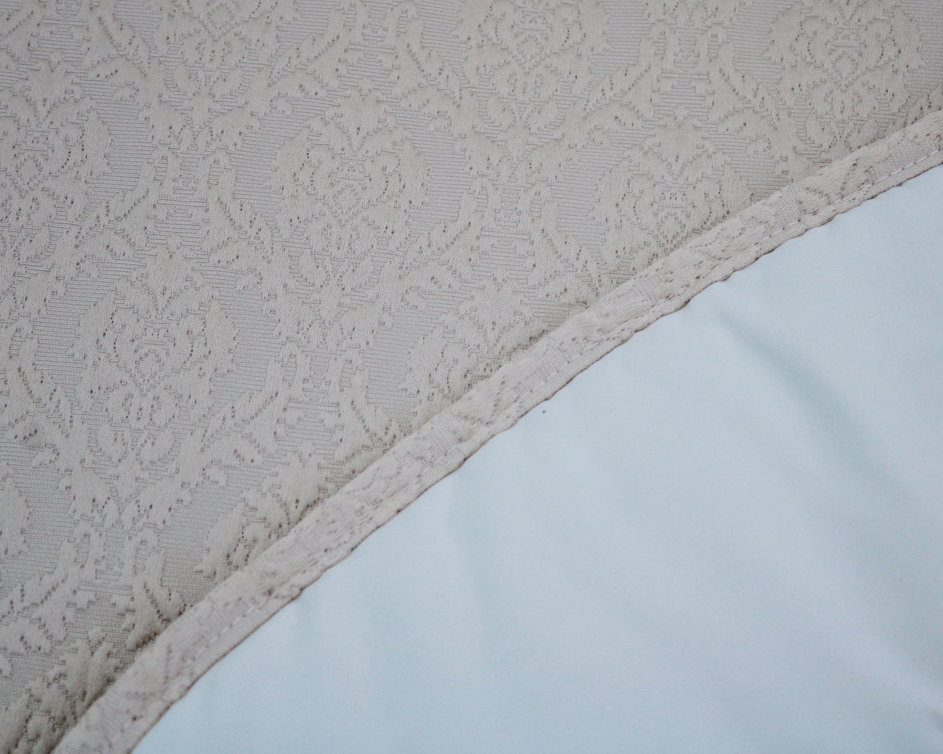 tecido bege com padrão floral e tecido branco liso unidos por costura