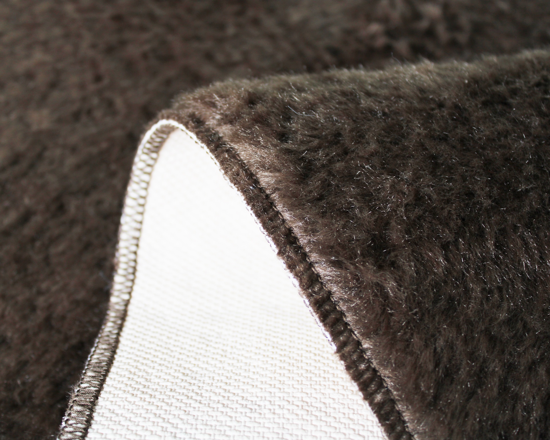 Tapete felpudo castanho escuro com acabamento em costura branca