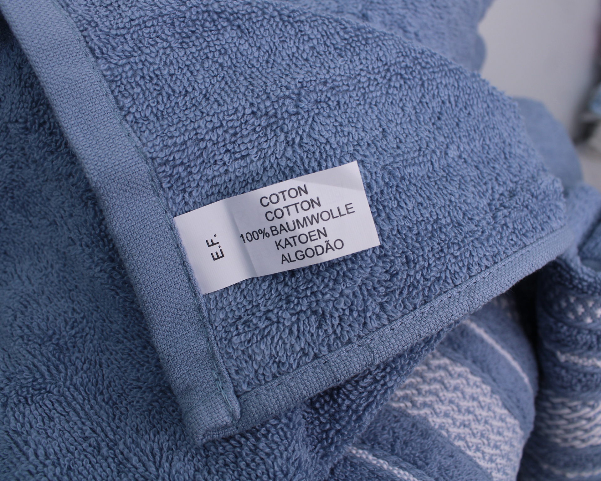 Toalha azul de algodão com etiqueta de composição em várias línguas