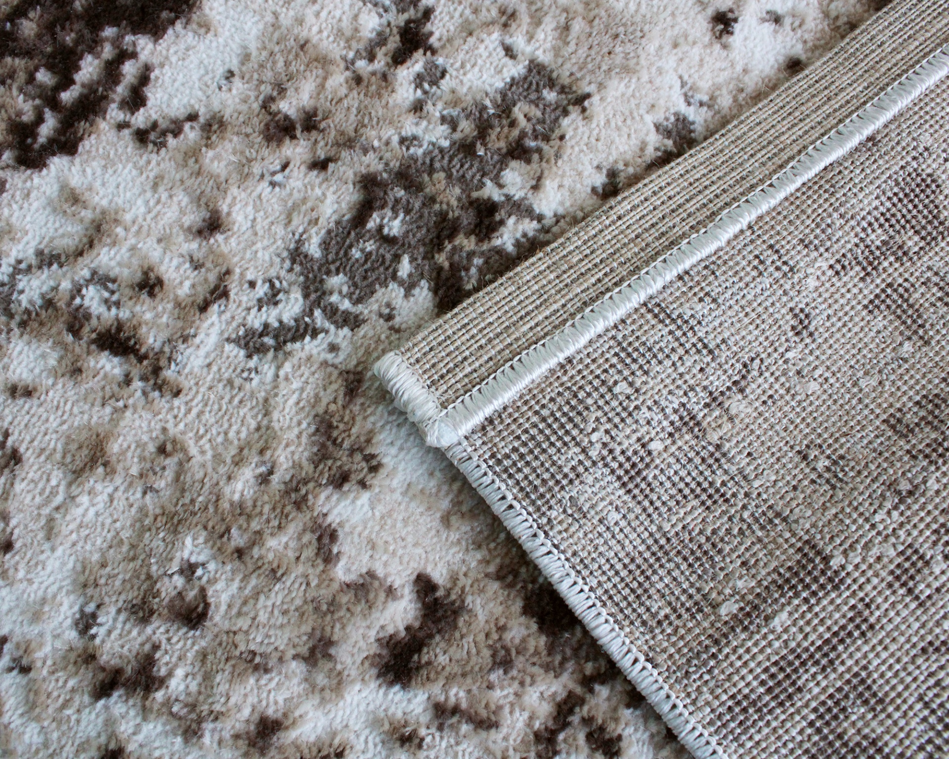 Tapete cinza e branco com borda dobrada mostrando o verso