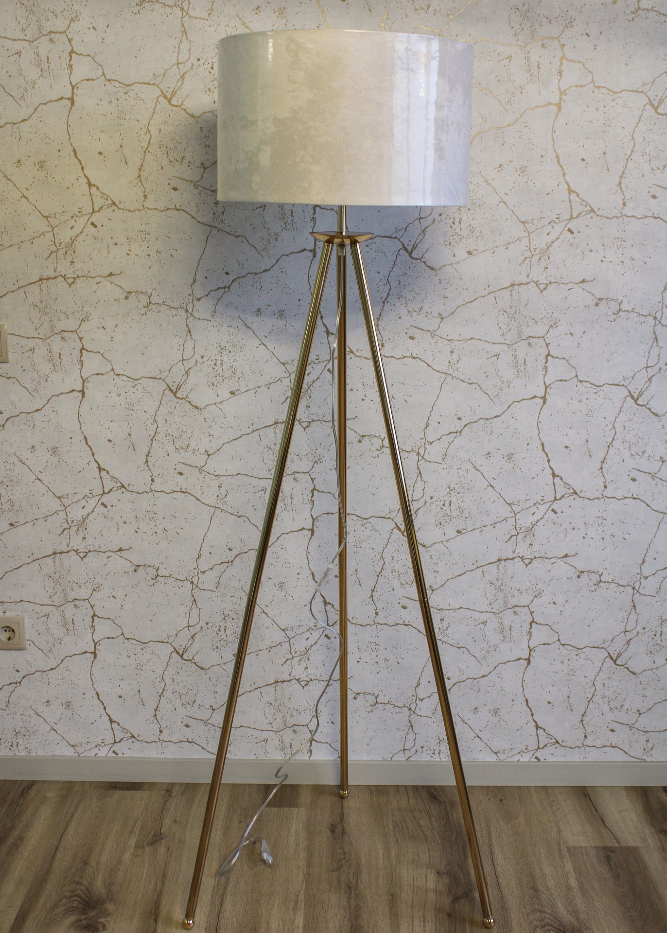 Candeeiro de pé dourado com cúpula branca e fundo de parede marmoreada