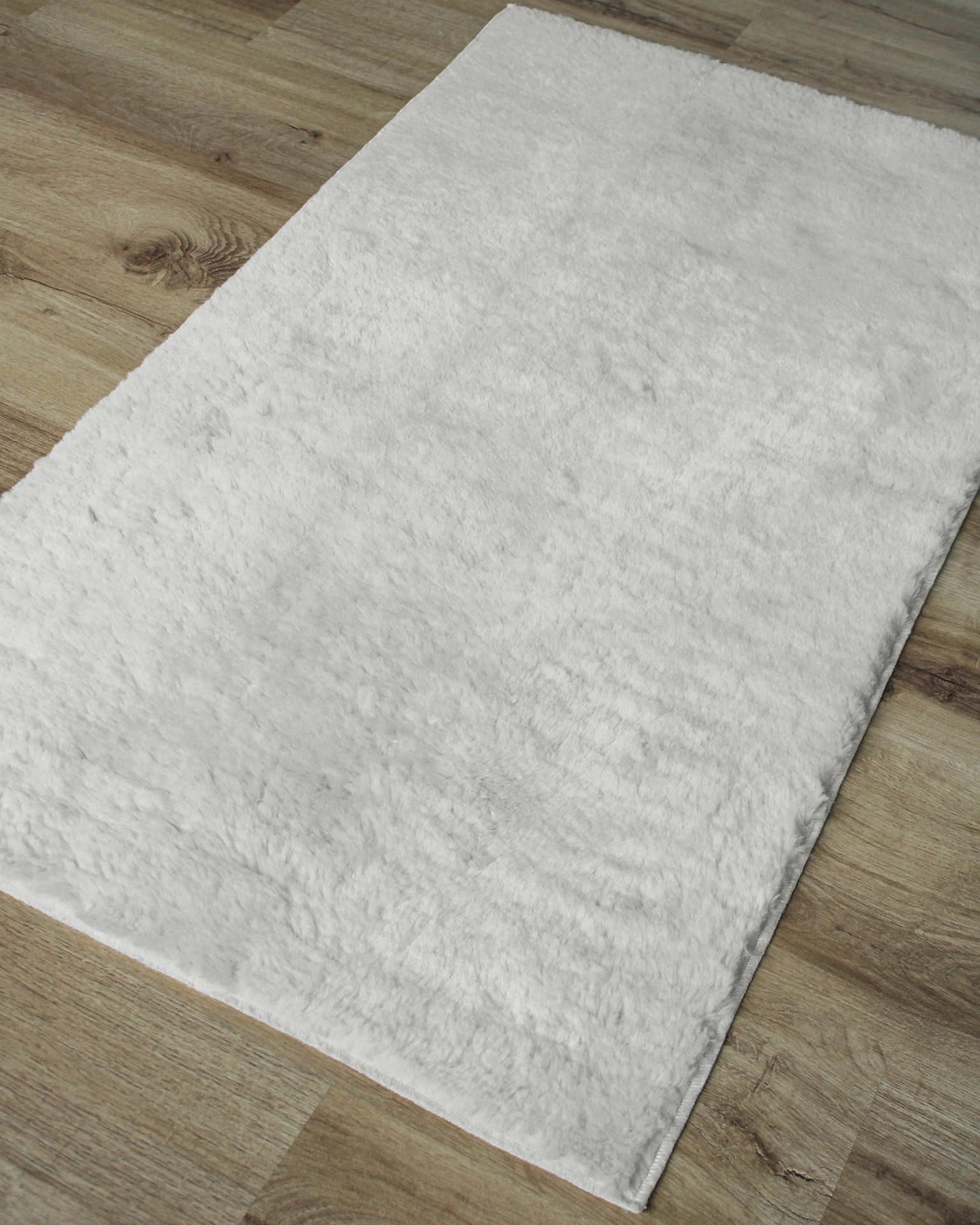 Tapete branco felpudo sobre chão de madeira clara