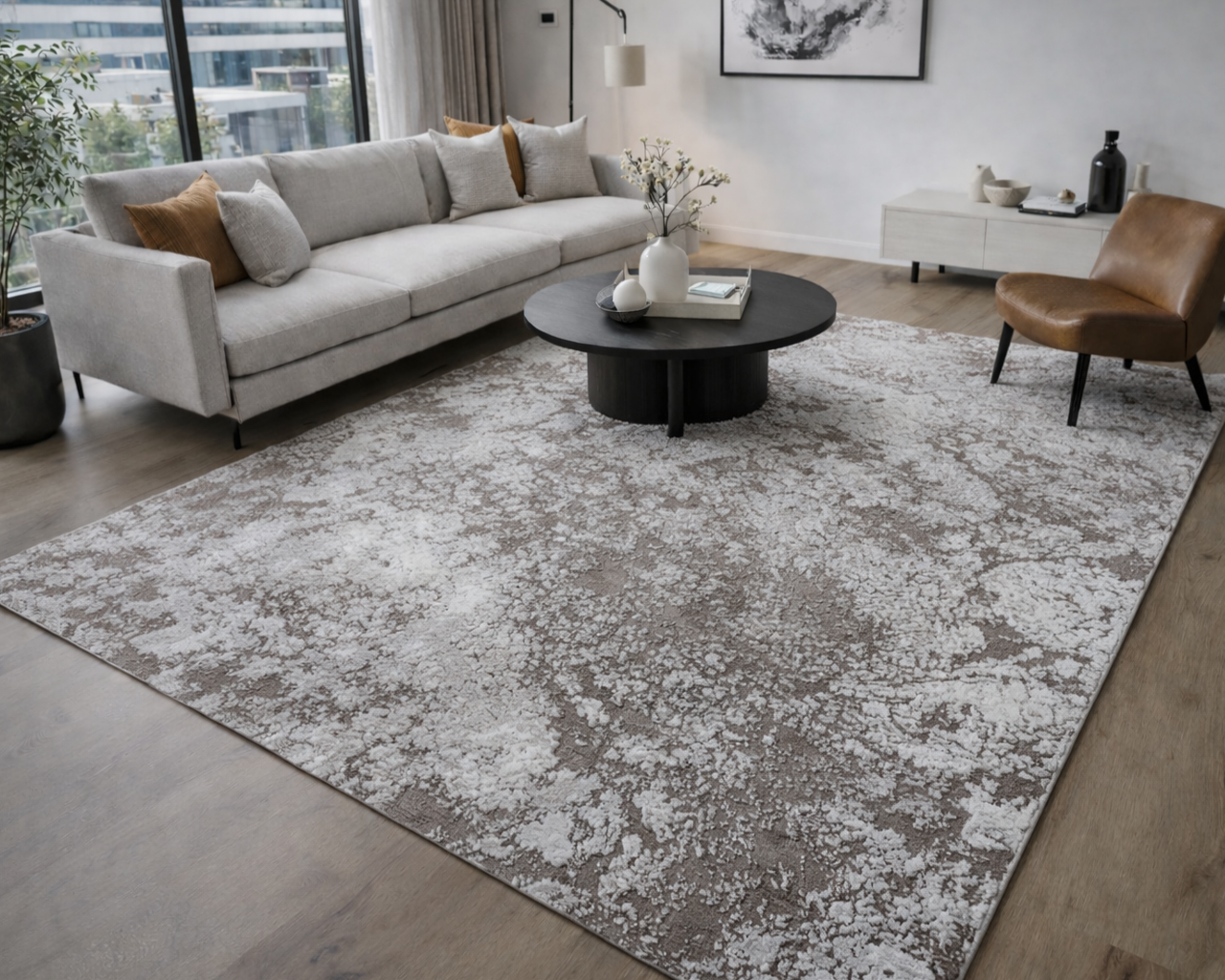 Sala de estar com sofá cinzento, tapete bege e cinzento, mesa de centro preta e cadeira castanha