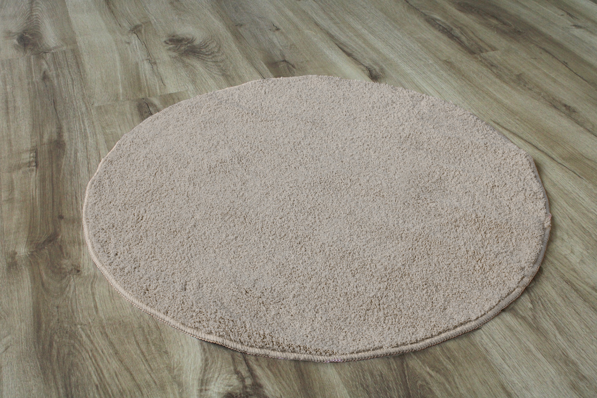 Tapete redondo bege claro sobre chão de madeira clara