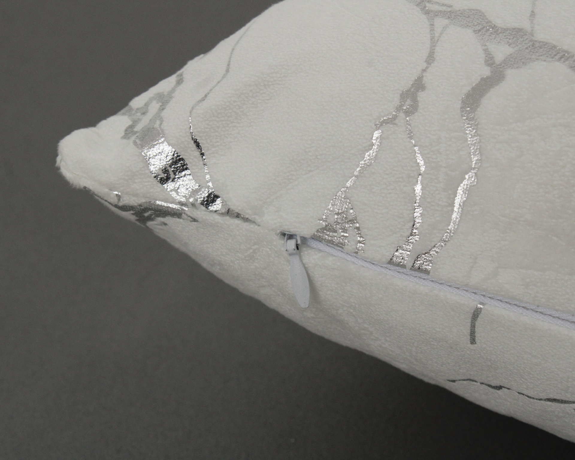 Almofada branca com padrão prateado e fecho de correr