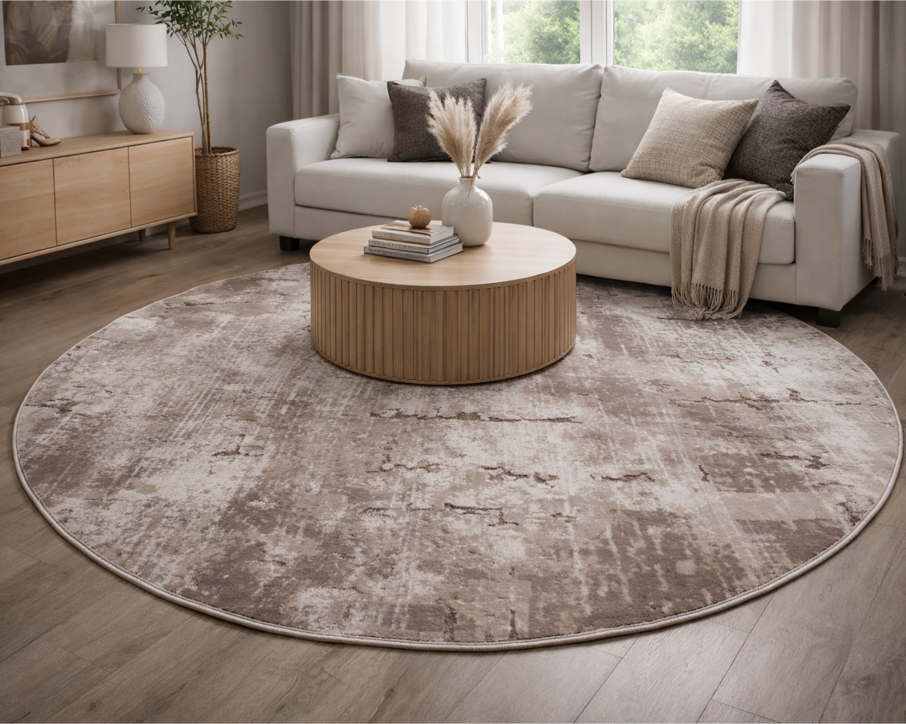 Tapete redondo castanho e bege num ambiente de sala com sofá cinza, mesa de centro em madeira clara e decoração
