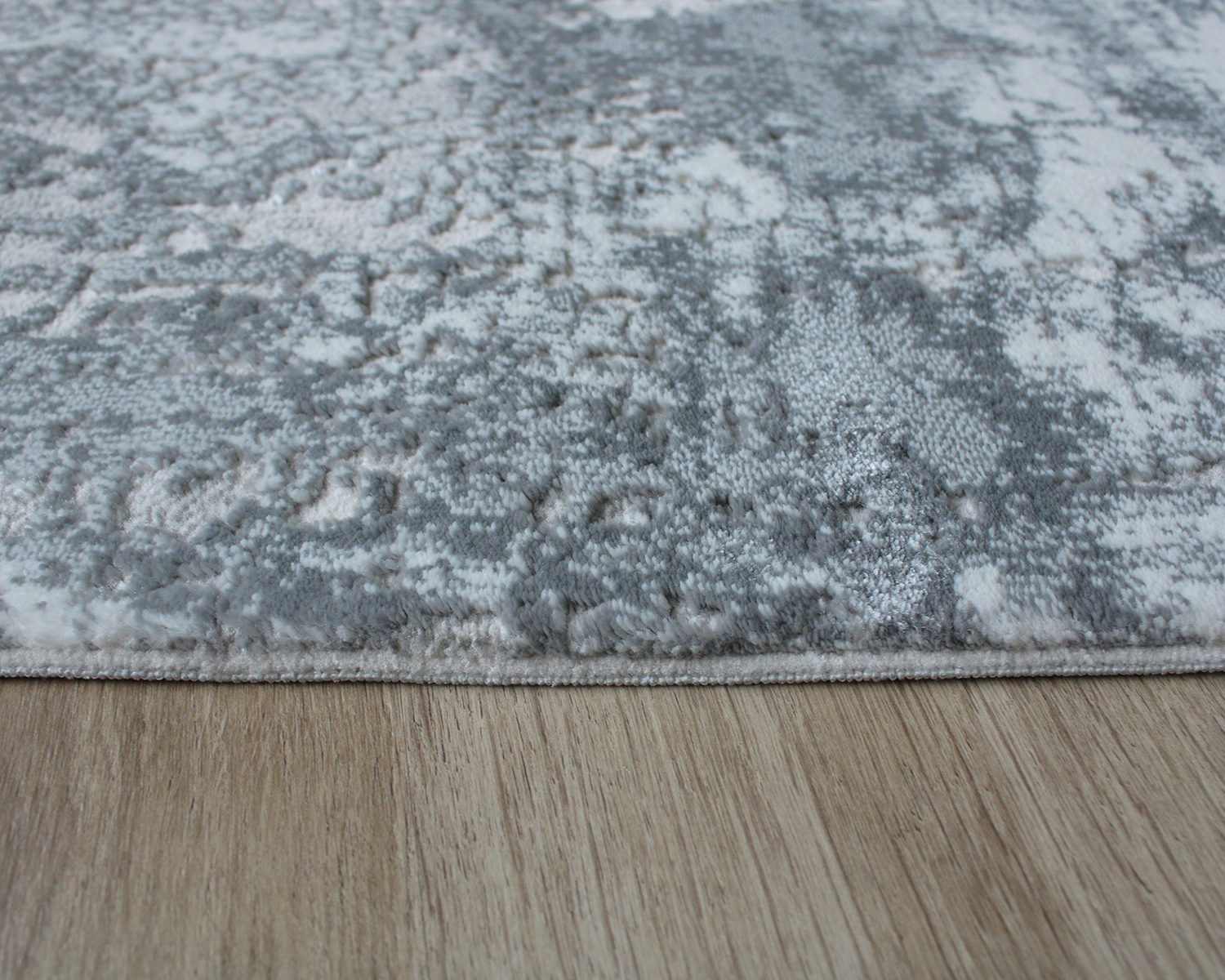 Tapete cinza com textura sobre chão de madeira clara