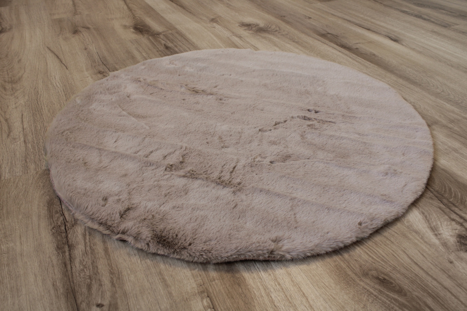 Tapete redondo cinza claro felpudo sobre pavimento de madeira clara