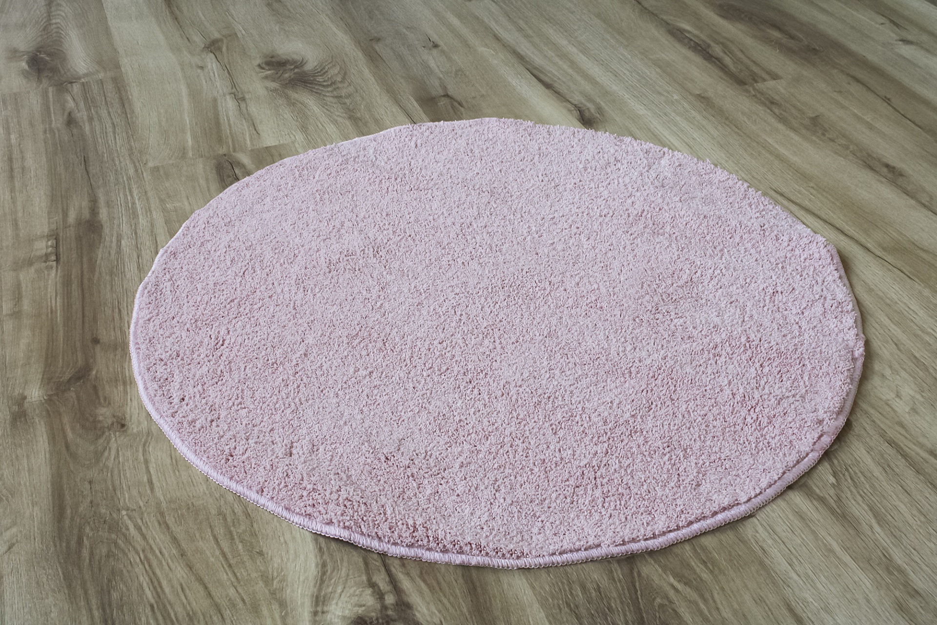 Tapete redondo rosa claro em chão de madeira clara