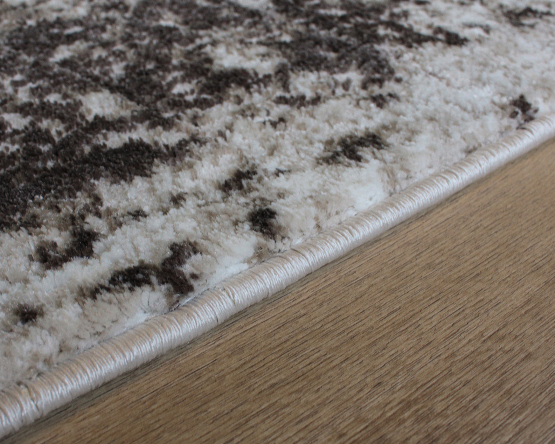 Tapete branco e castanho com padrão abstrato sobre piso de madeira