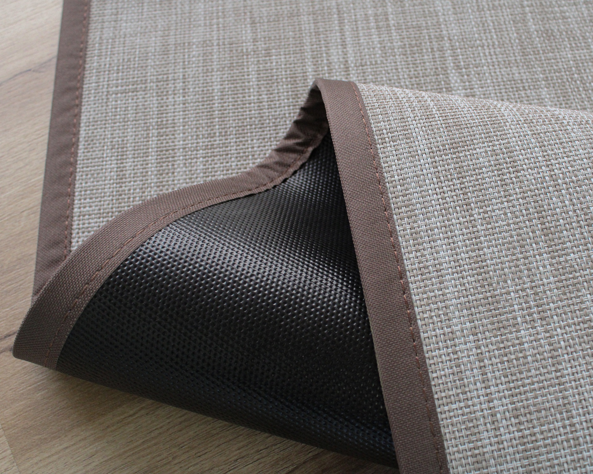 Tapete bege com bordas castanhas e base antiderrapante preta