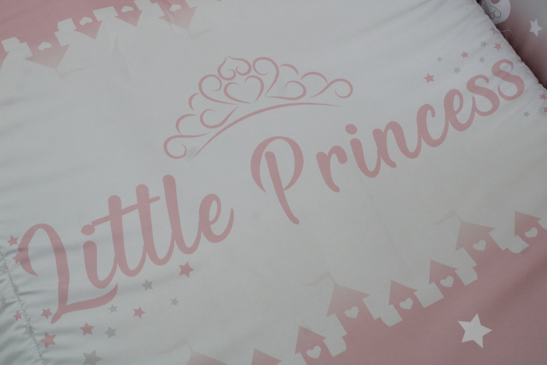 Tecido com design infantil rosa e branco com texto 'Little Princess' e castelos.