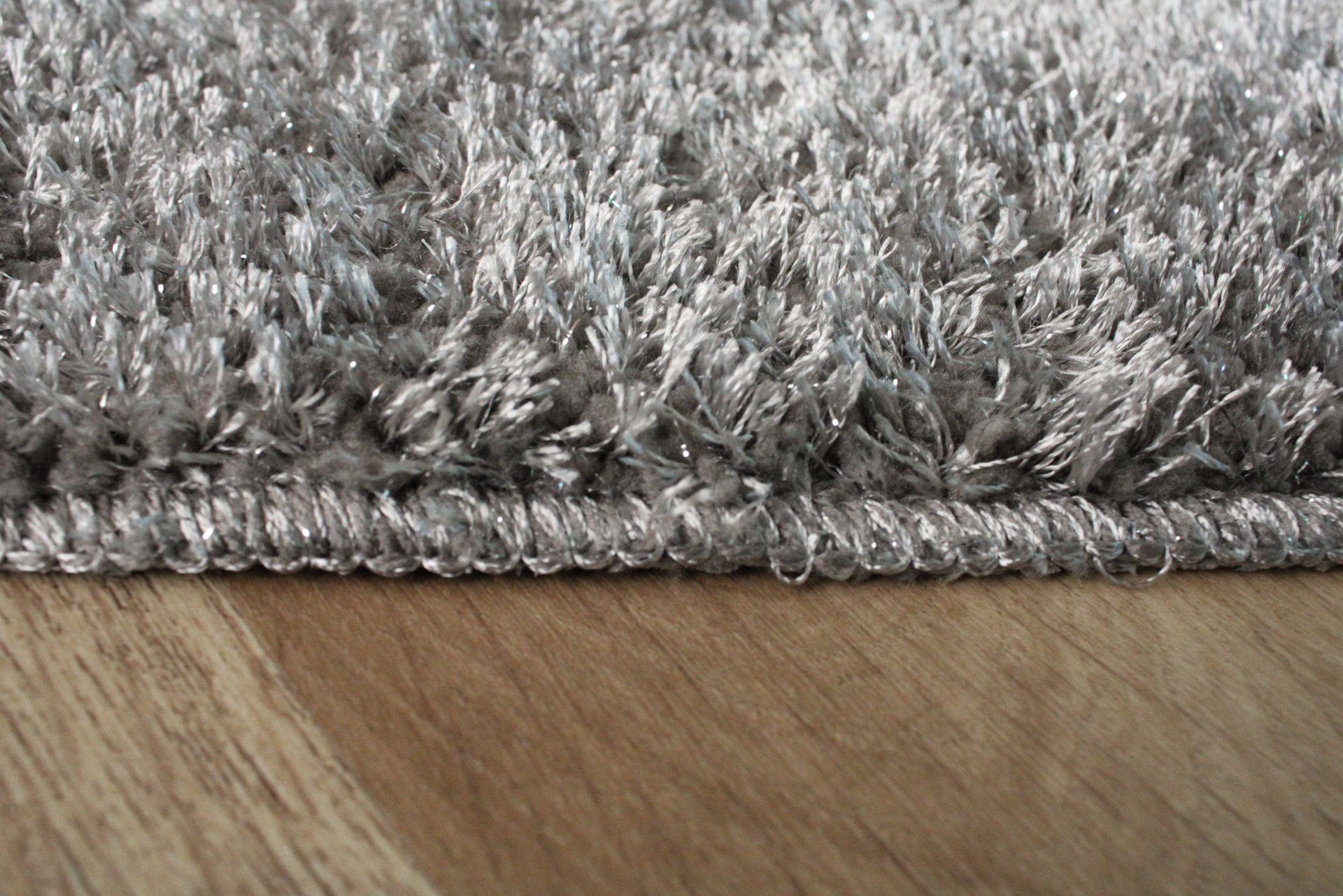 Tapete cinza felpudo sobre chão de madeira clara