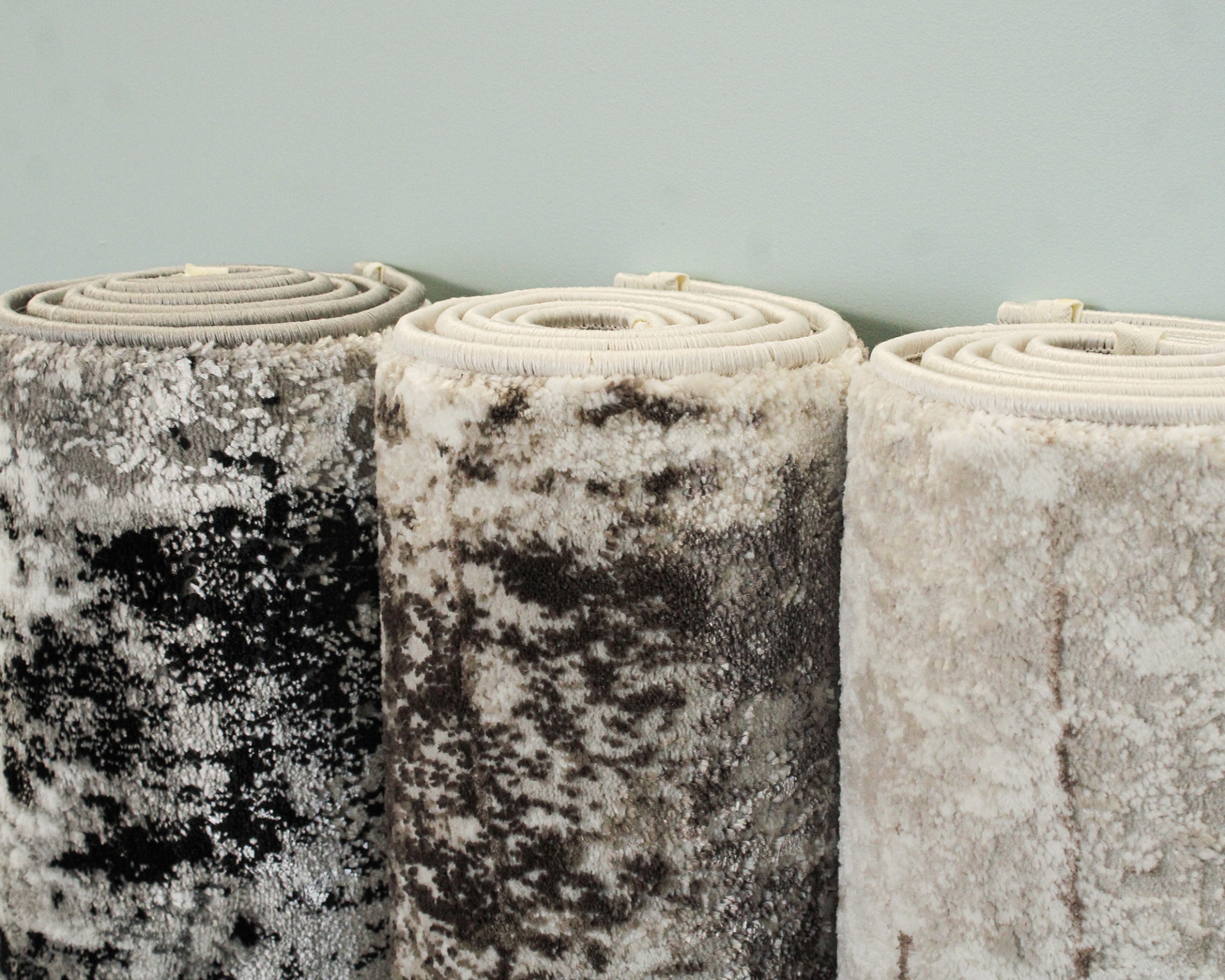 Três tapetes enrolados com padrão cinza e bege