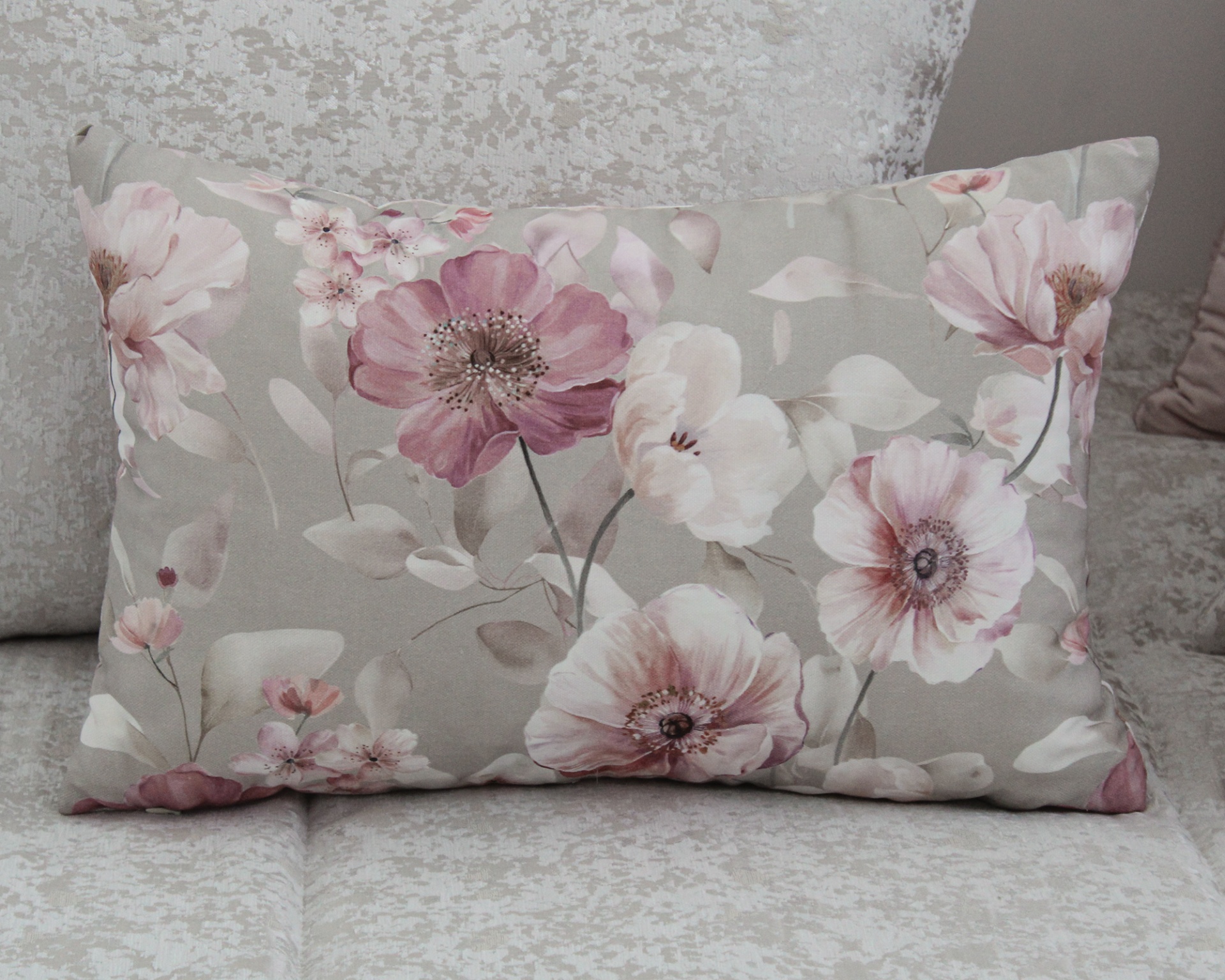 Almofada floral em tons rosa e branco sobre sofá bege