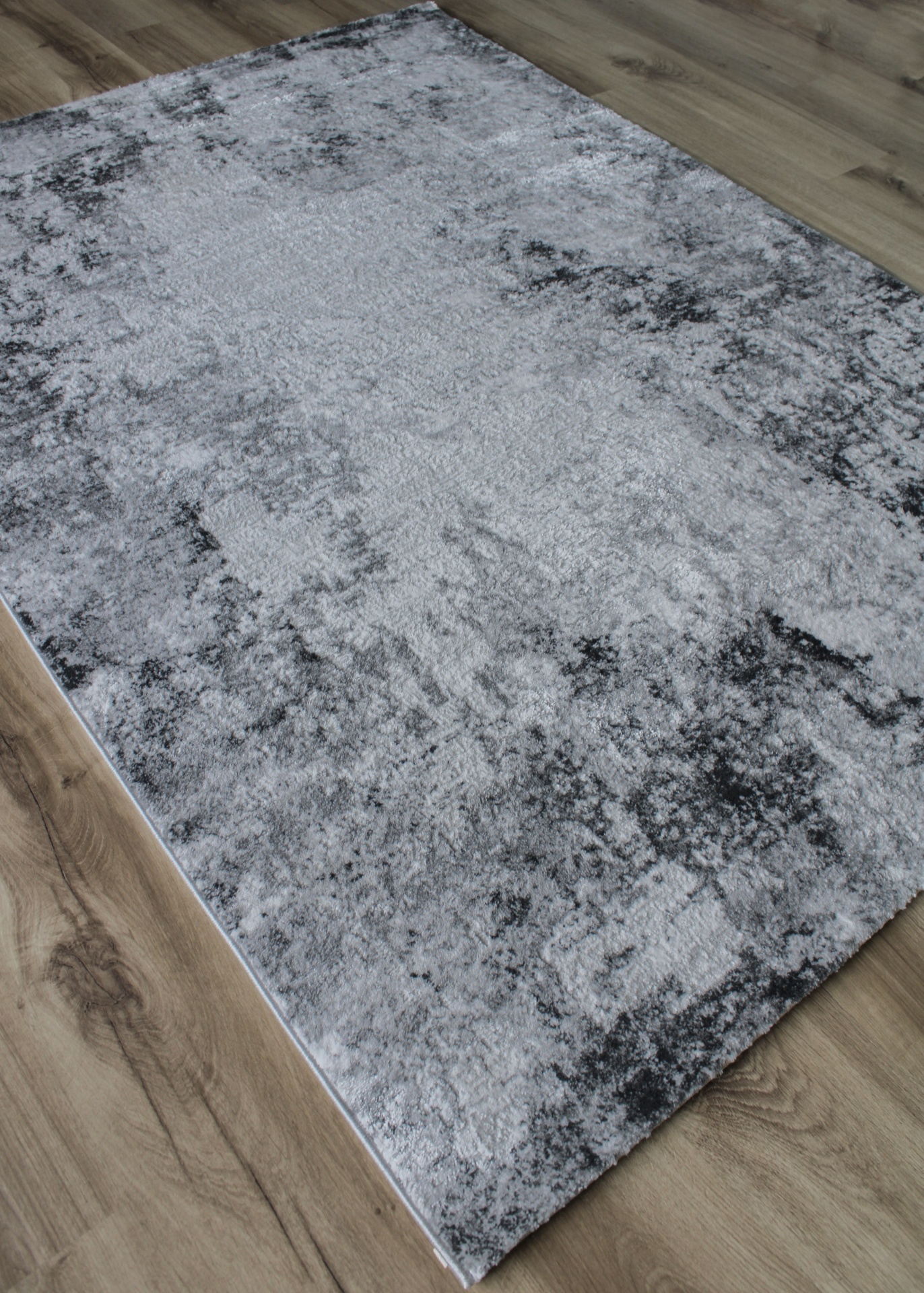 Tapete cinza e preto com padrão abstrato em chão de madeira
