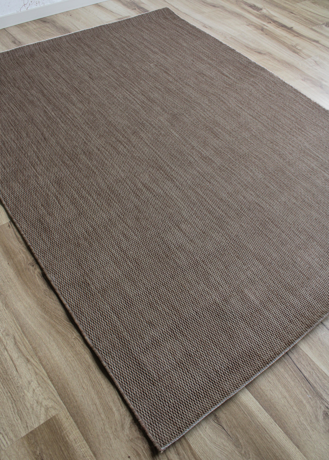 Tapete castanho sobre chão de madeira clara